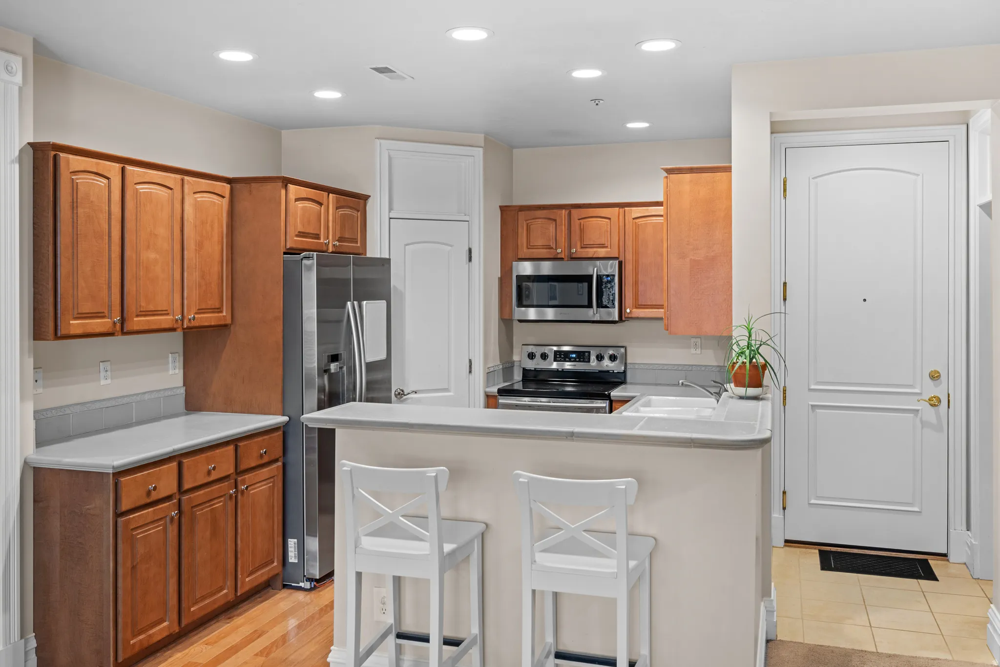 Kitchen featuring wood cabinetry, stainless steel appliances, and a breakfast bar with solid surface countertops
