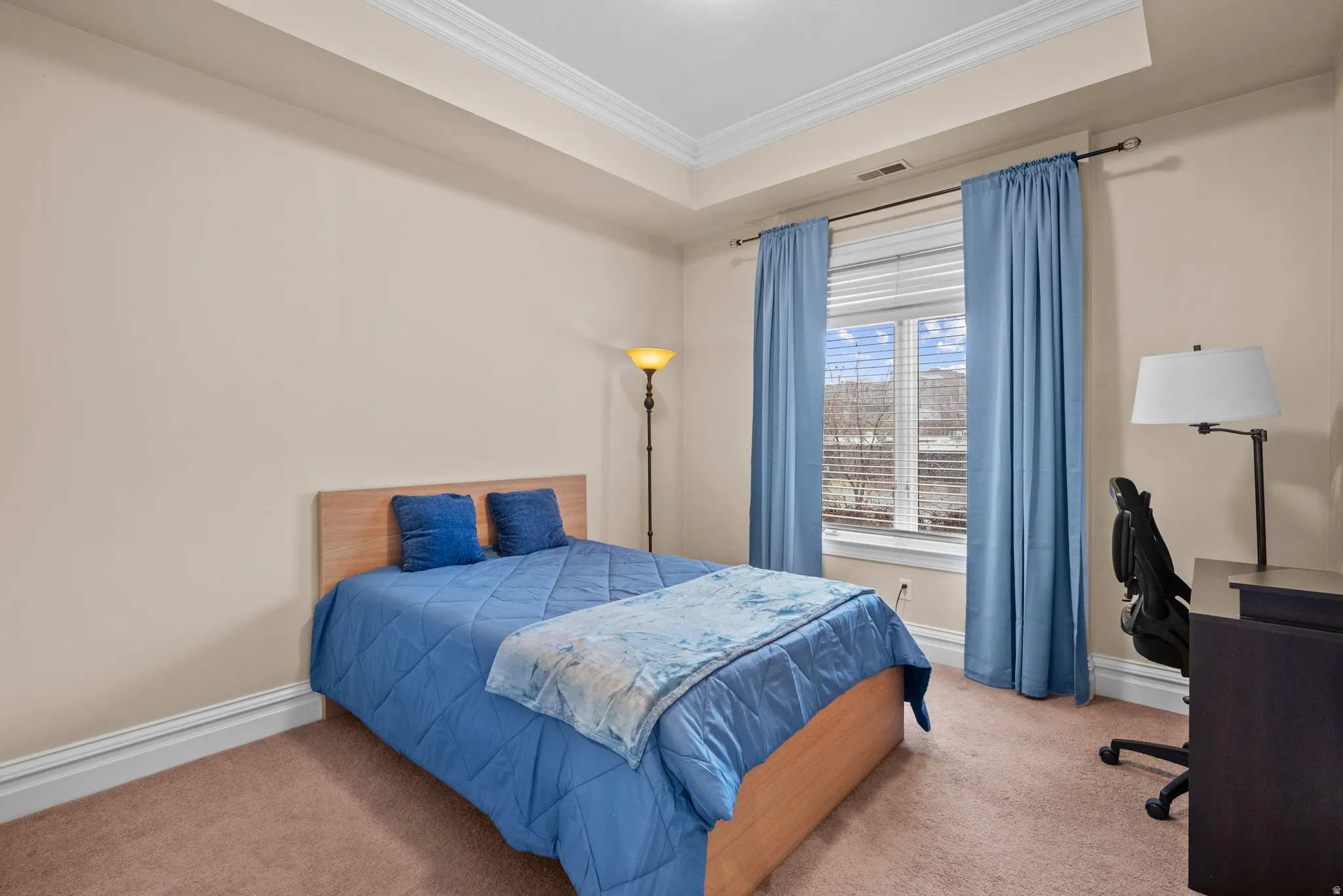 Bedroom with crown molding, a raised ceiling, carpet, and a desk