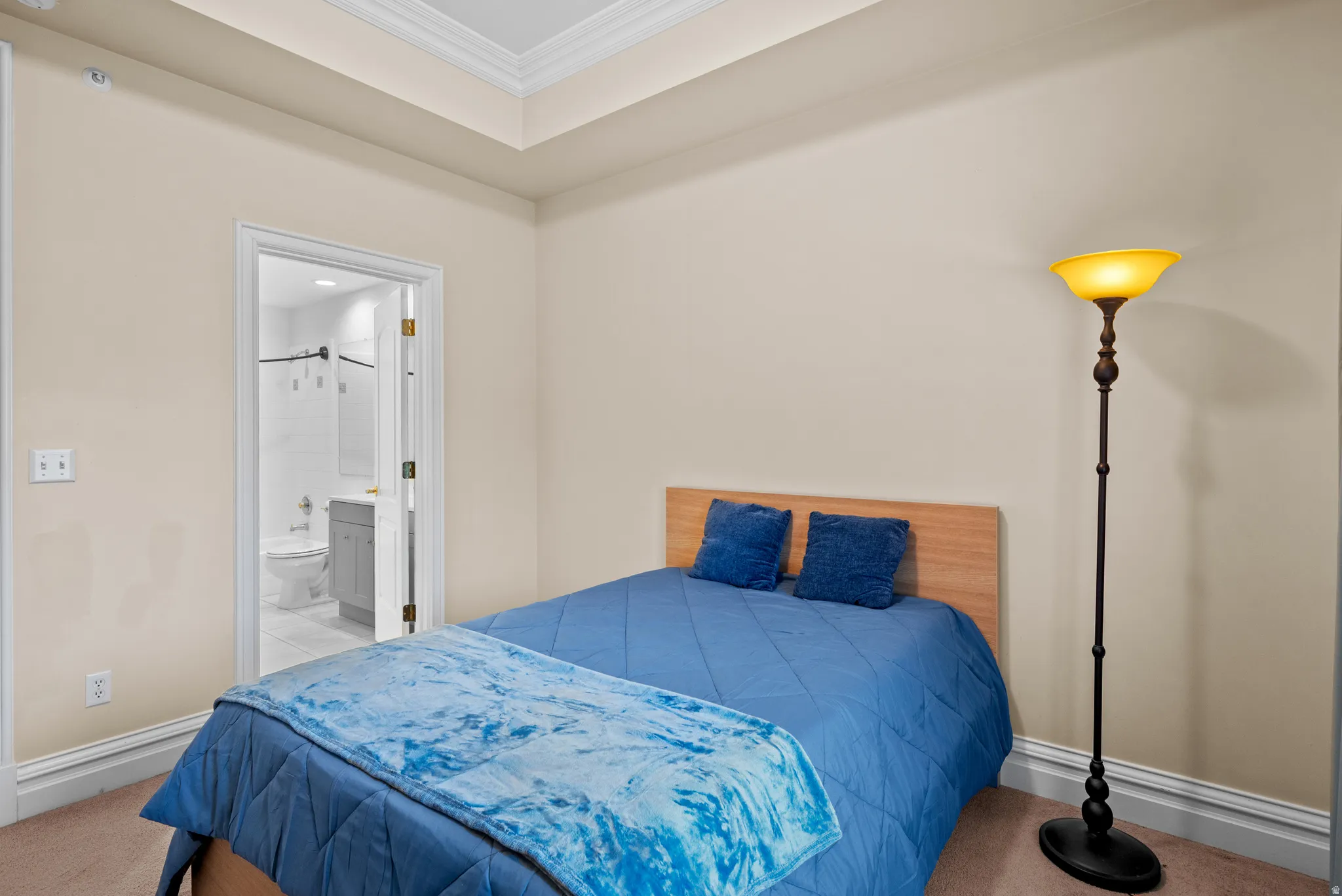 Bedroom with crown molding, connected bathroom, and carpet flooring