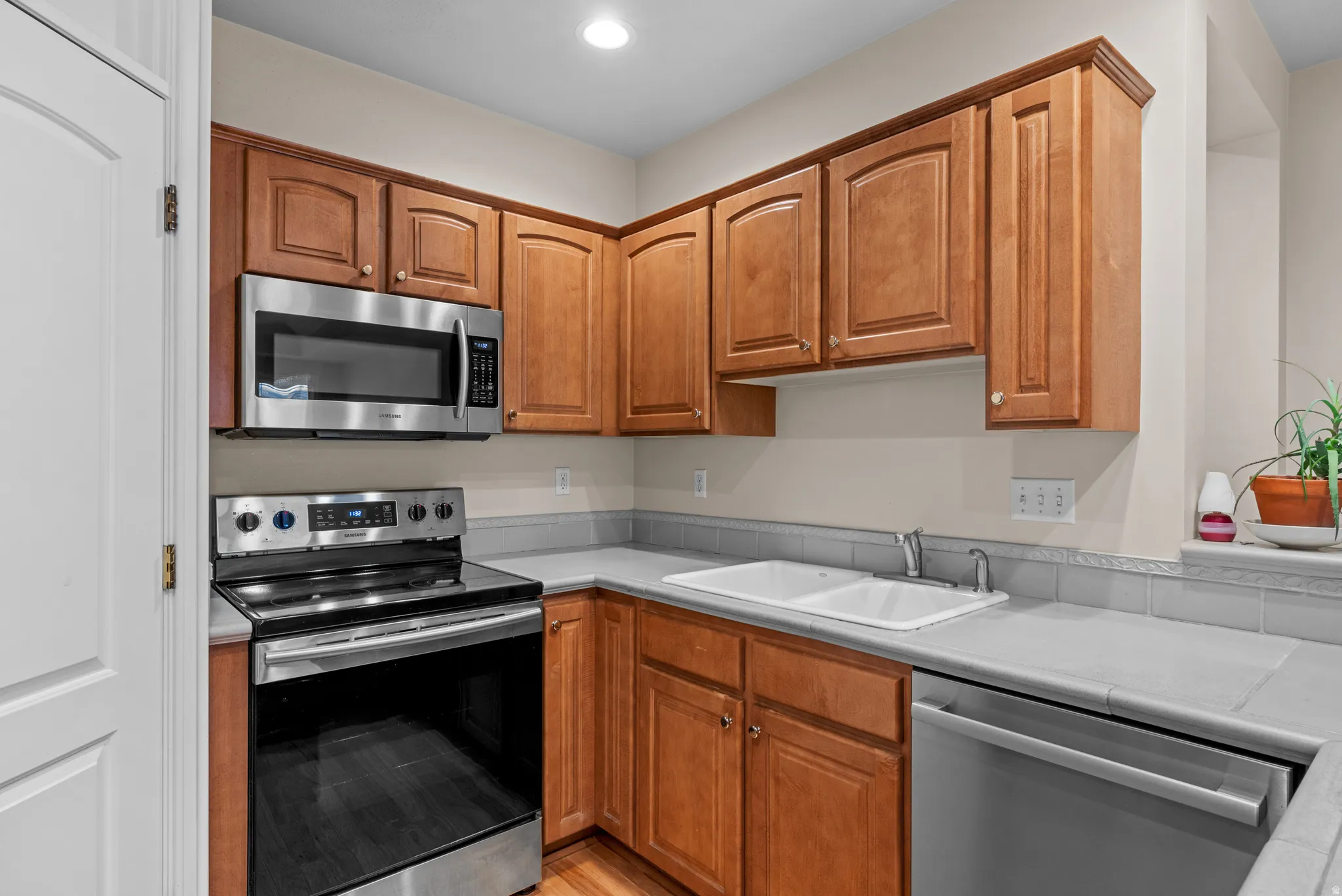 Kitchen with stainless steel appliances, light countertops, wood finish cabinetry, and recessed lighting