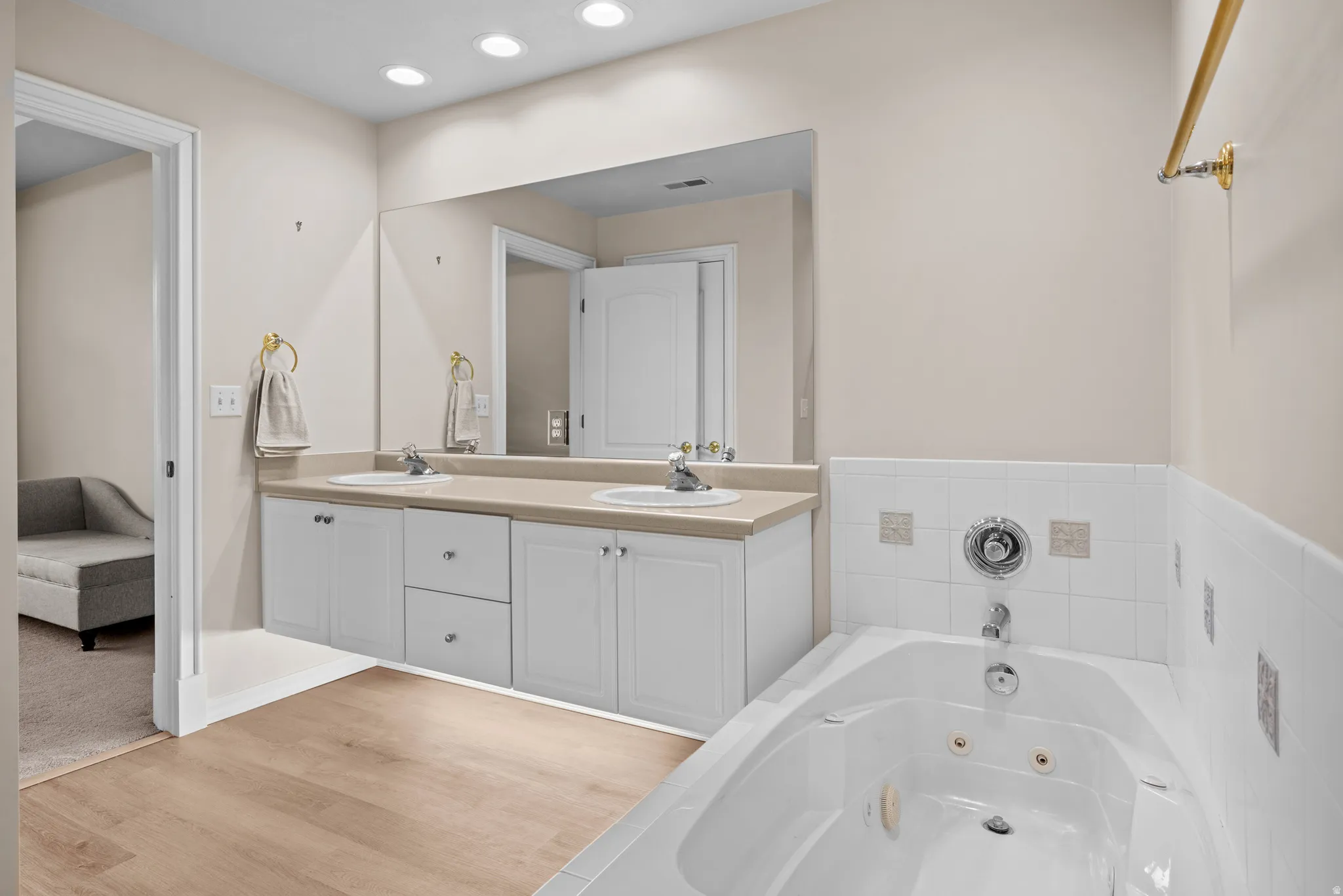 Full bathroom with ensuite bath, double vanity, a jetted tub, recessed lighting, and light wood-style flooring