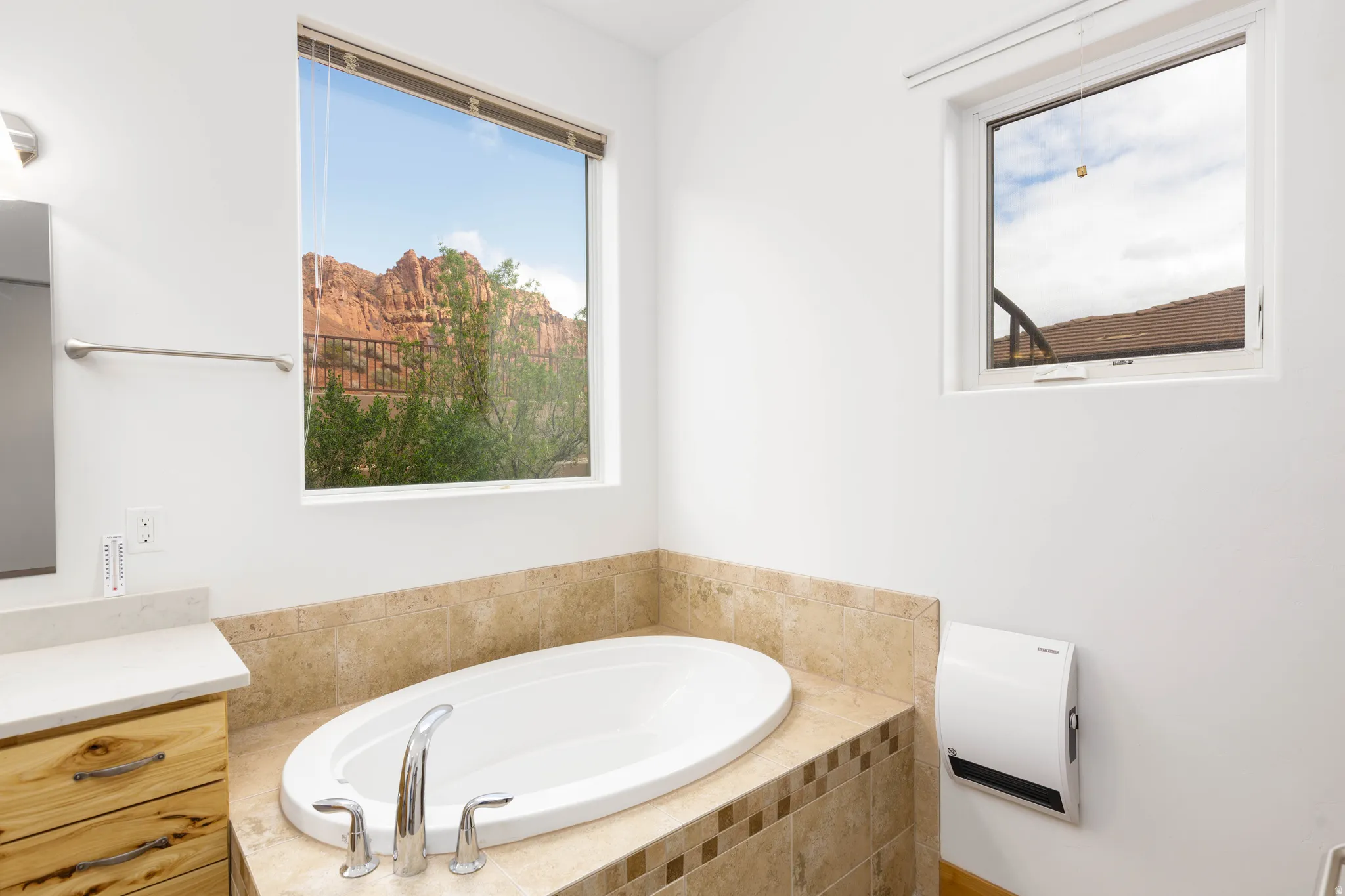 Bathroom with vanity, a bath, and healthy amount of natural light