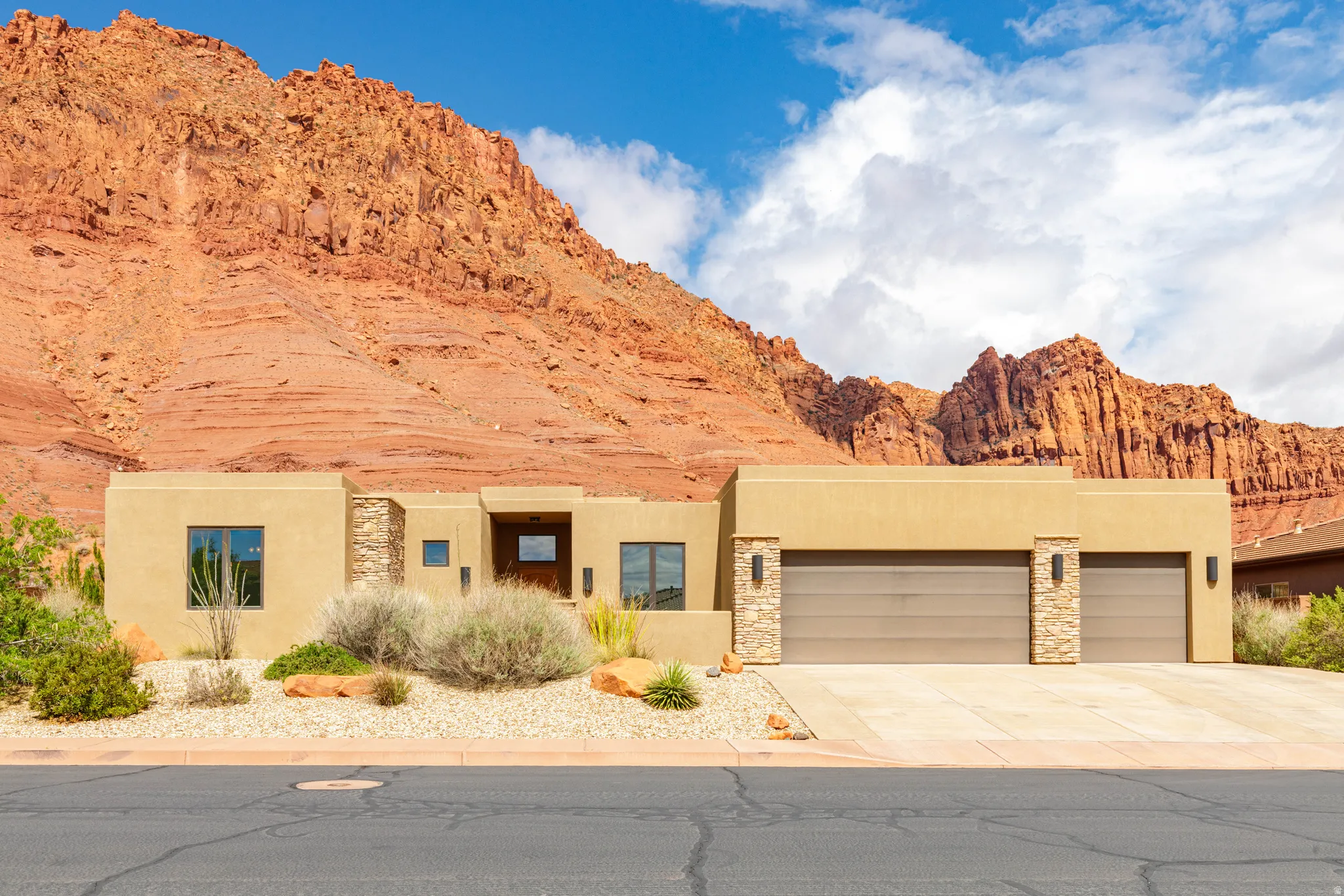 View of front of home featuring a garage, stone siding, stucco siding, and a mountain view