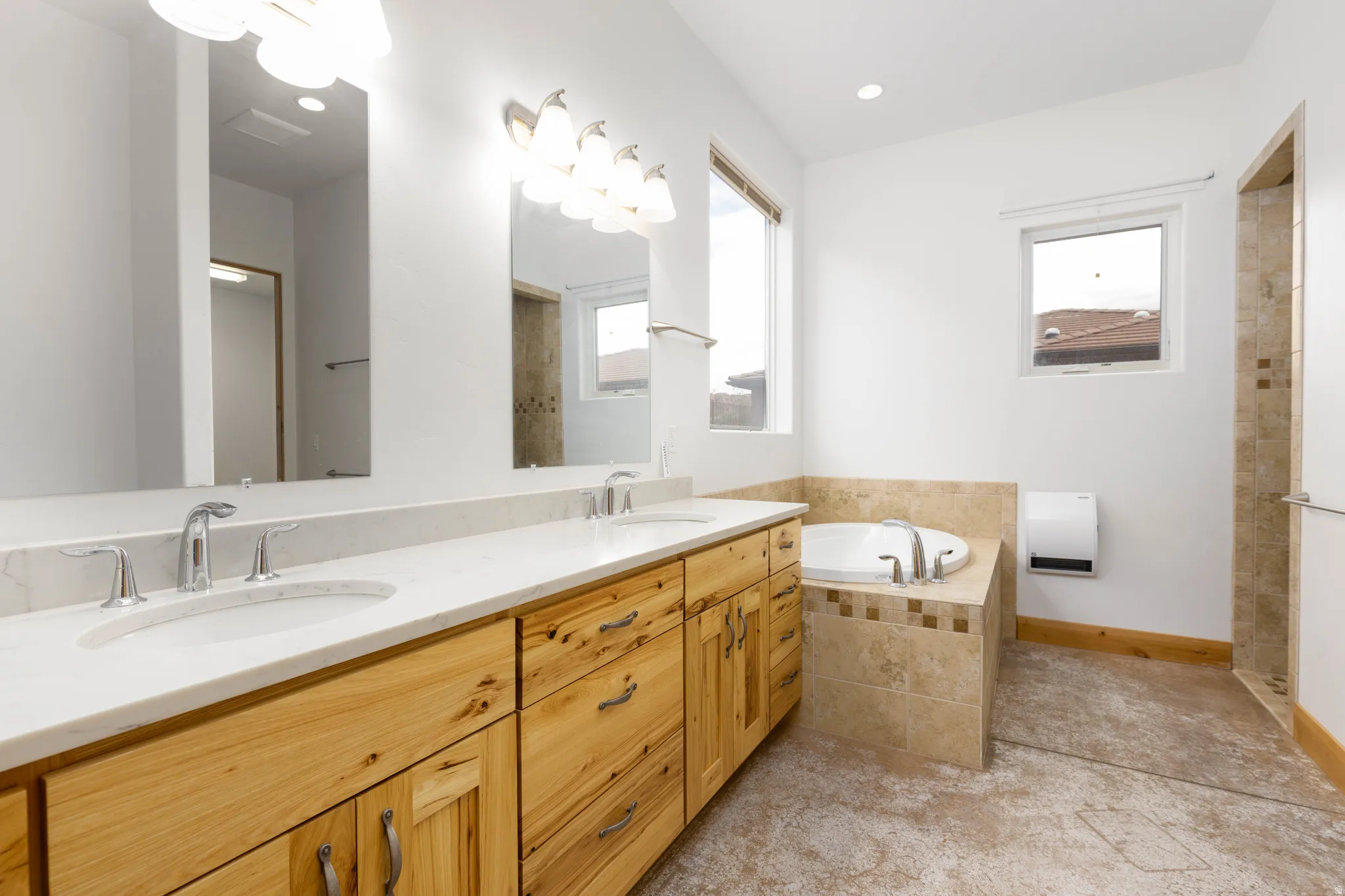 Bathroom featuring double vanity, a bath, heating unit, and a tile shower