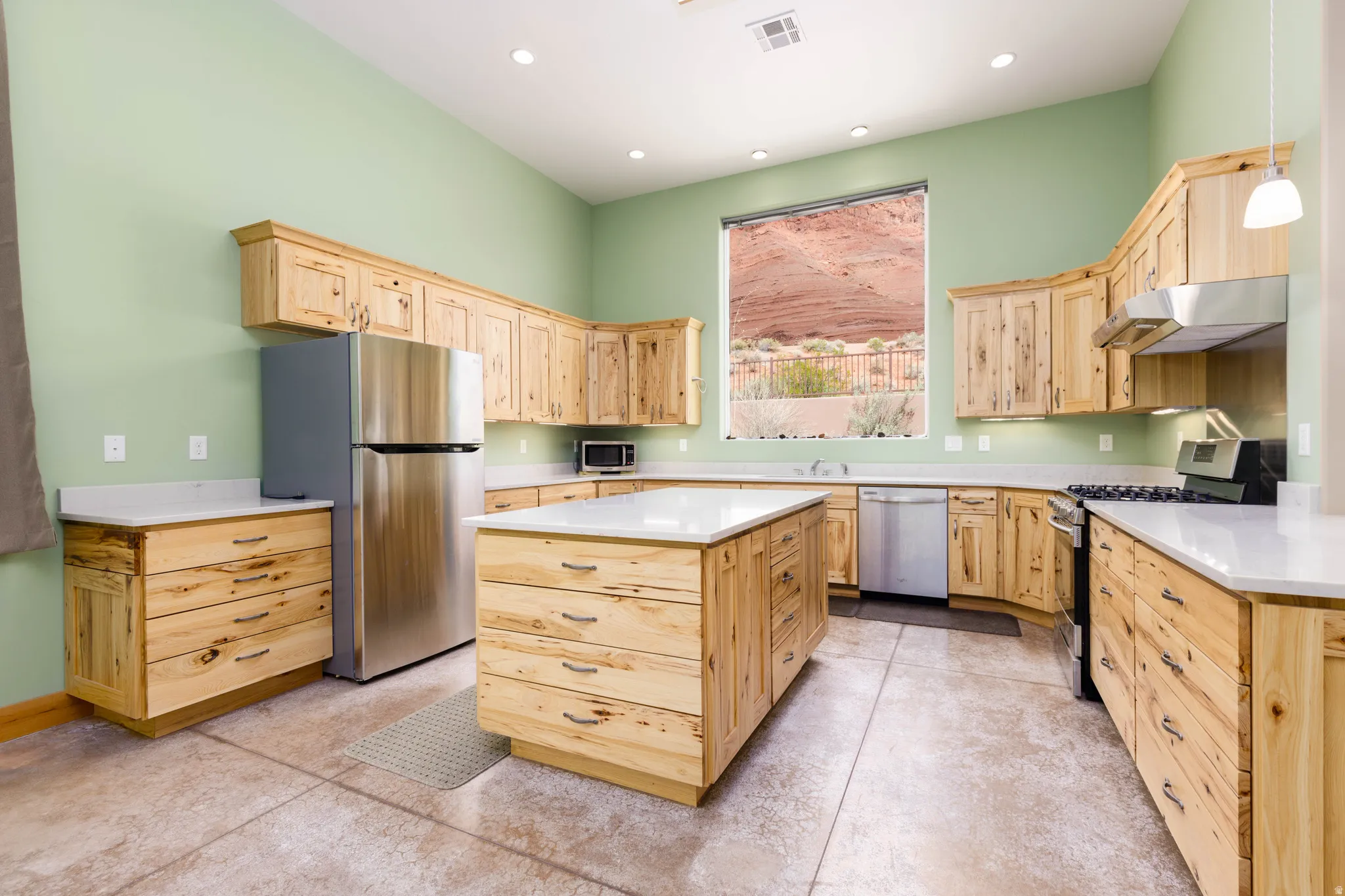 Kitchen featuring light wood finish cabinetry, stainless steel appliances, a kitchen island, and recessed lighting