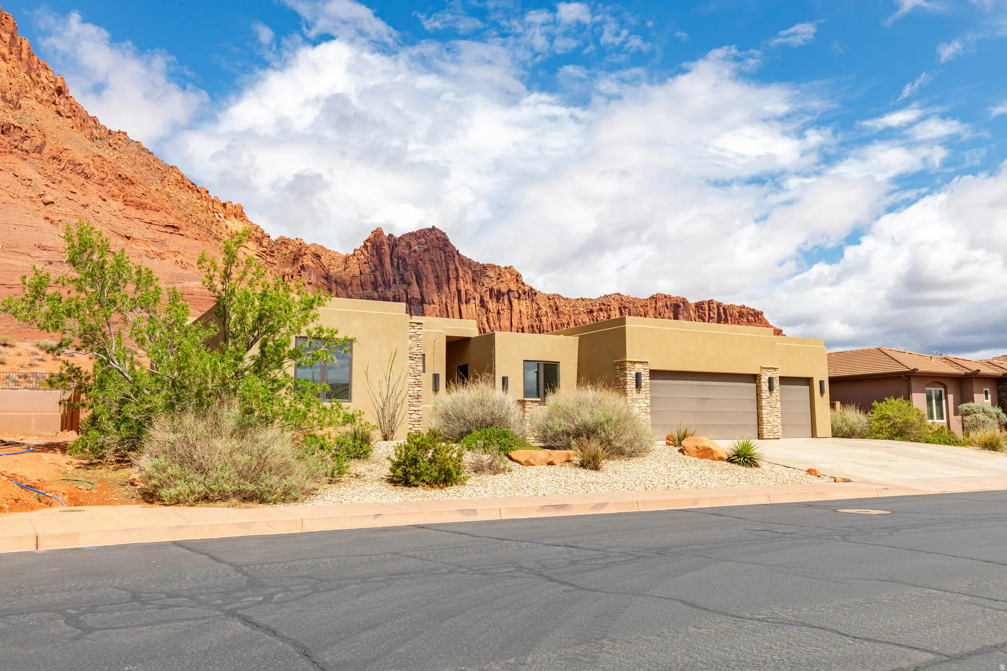Pueblo-style house featuring stucco siding, a garage, a mountain view, and concrete driveway