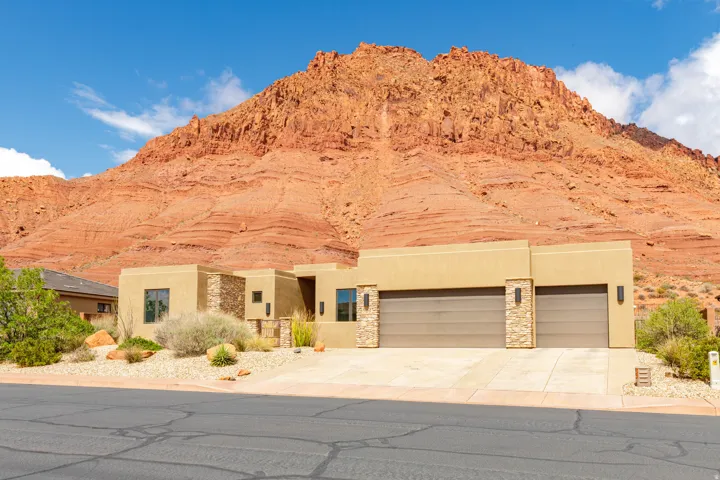 View of front facade featuring a garage, stucco siding, stone siding, and a mountain view