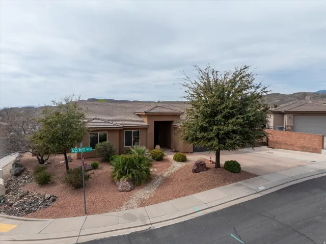 Single story home featuring concrete driveway, a tile roof, stucco siding, a mountain view, and an attached garage
