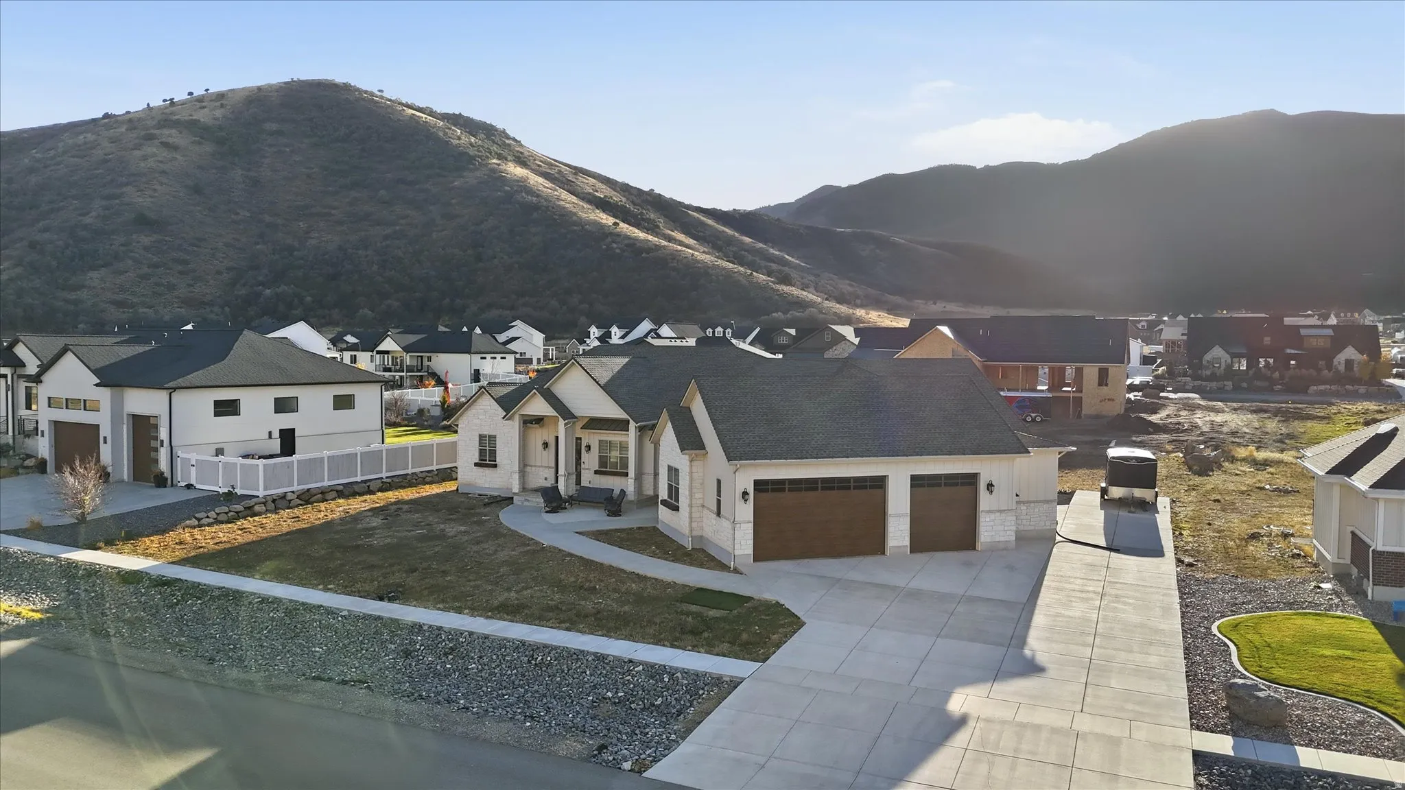 View of front of property featuring a garage, a residential view, concrete driveway, stone siding, and a mountain view
