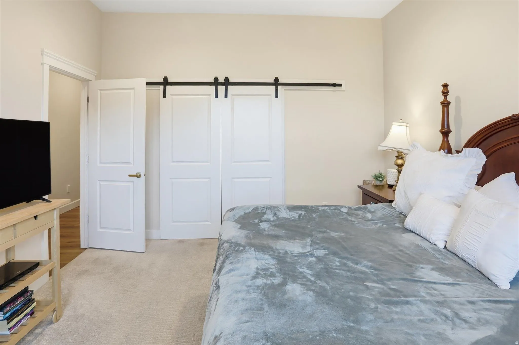 Bedroom featuring a barn door and light colored carpet