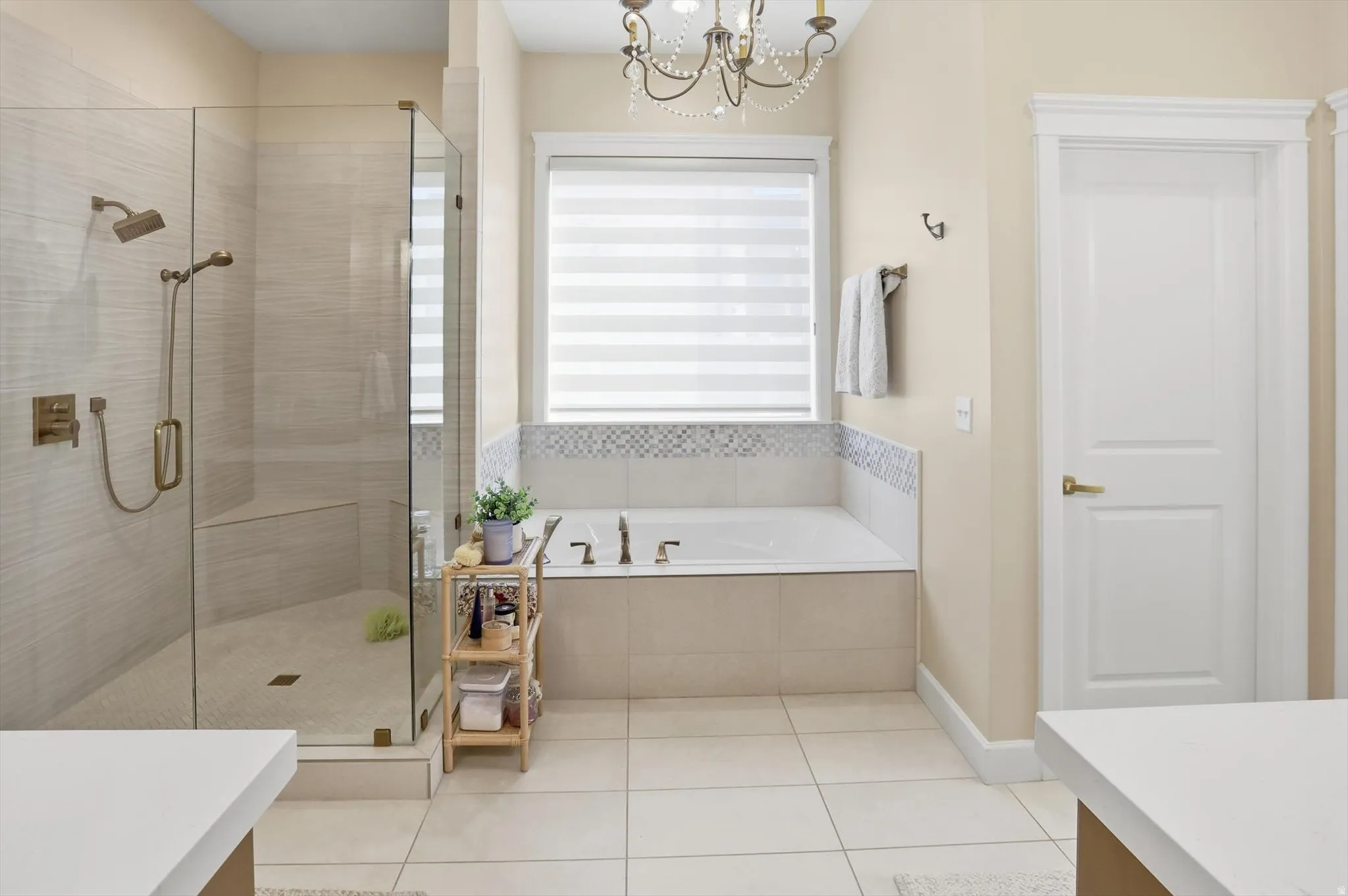 Bathroom featuring a chandelier, a stall shower, a bath, light tile patterned floors, and vanity