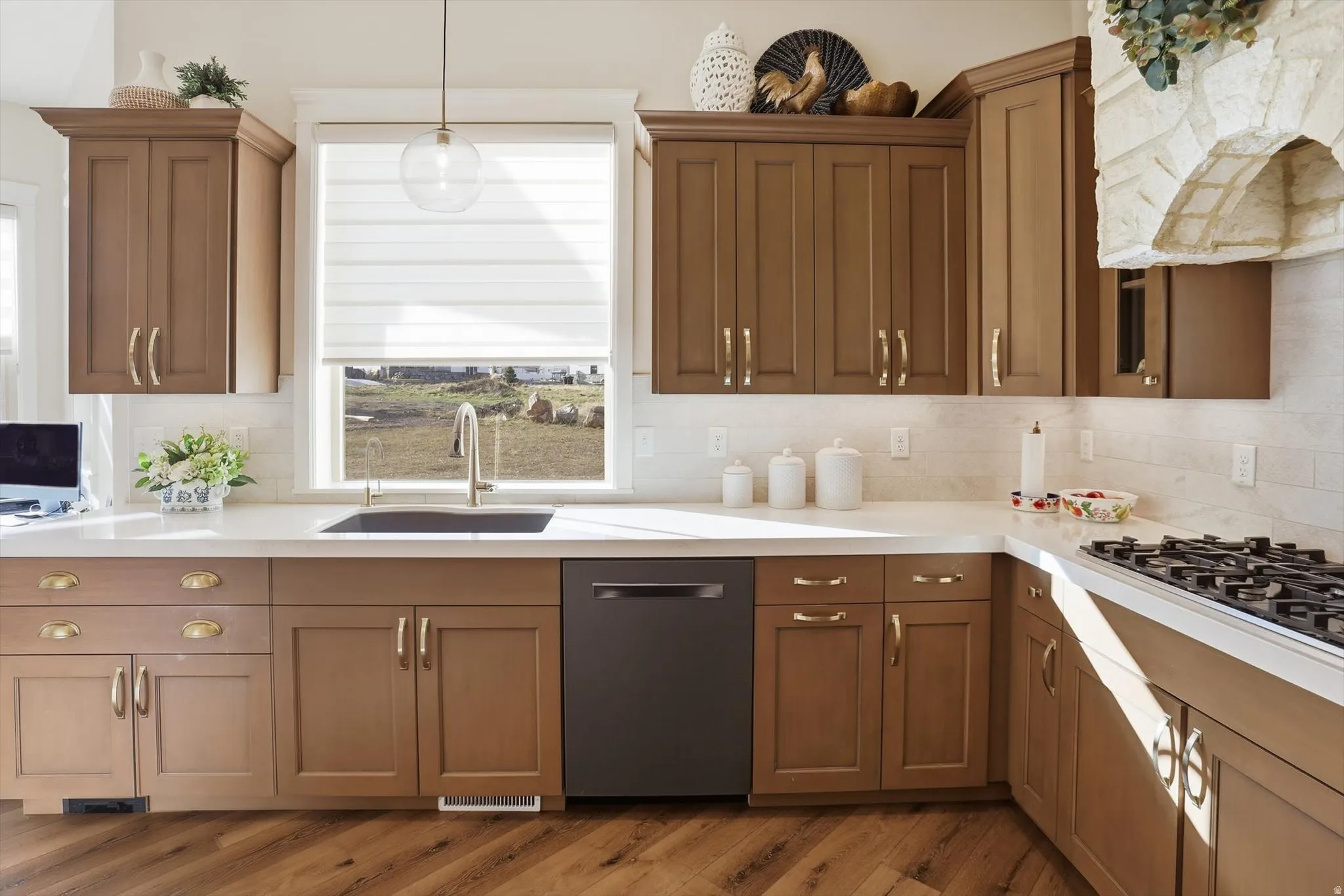 Kitchen featuring dishwasher, hanging light fixtures, tasteful backsplash, dark wood-type flooring, and black gas cooktop