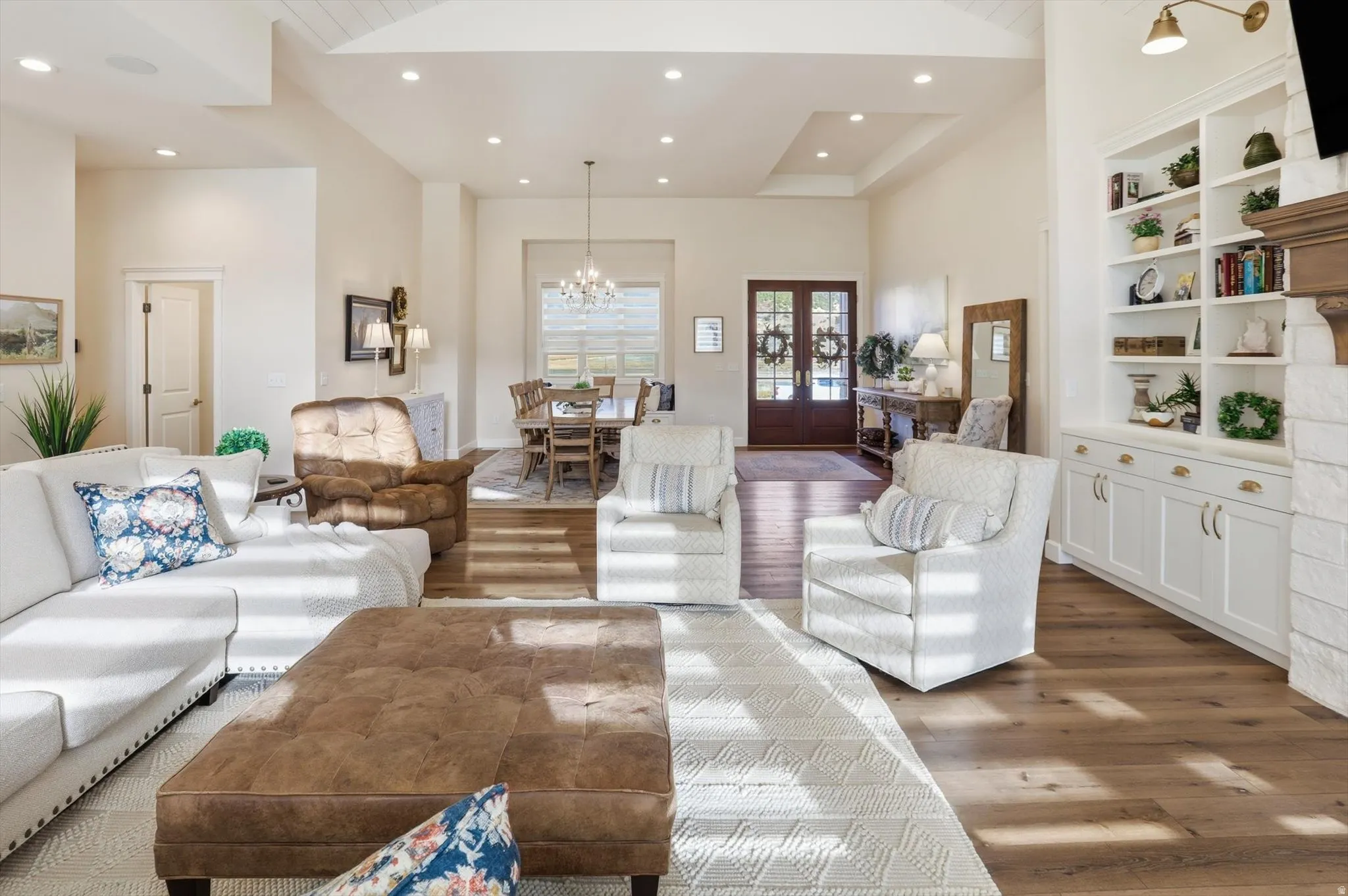 Living room featuring hanging lights, wood finished floors, built in shelves, and french doors