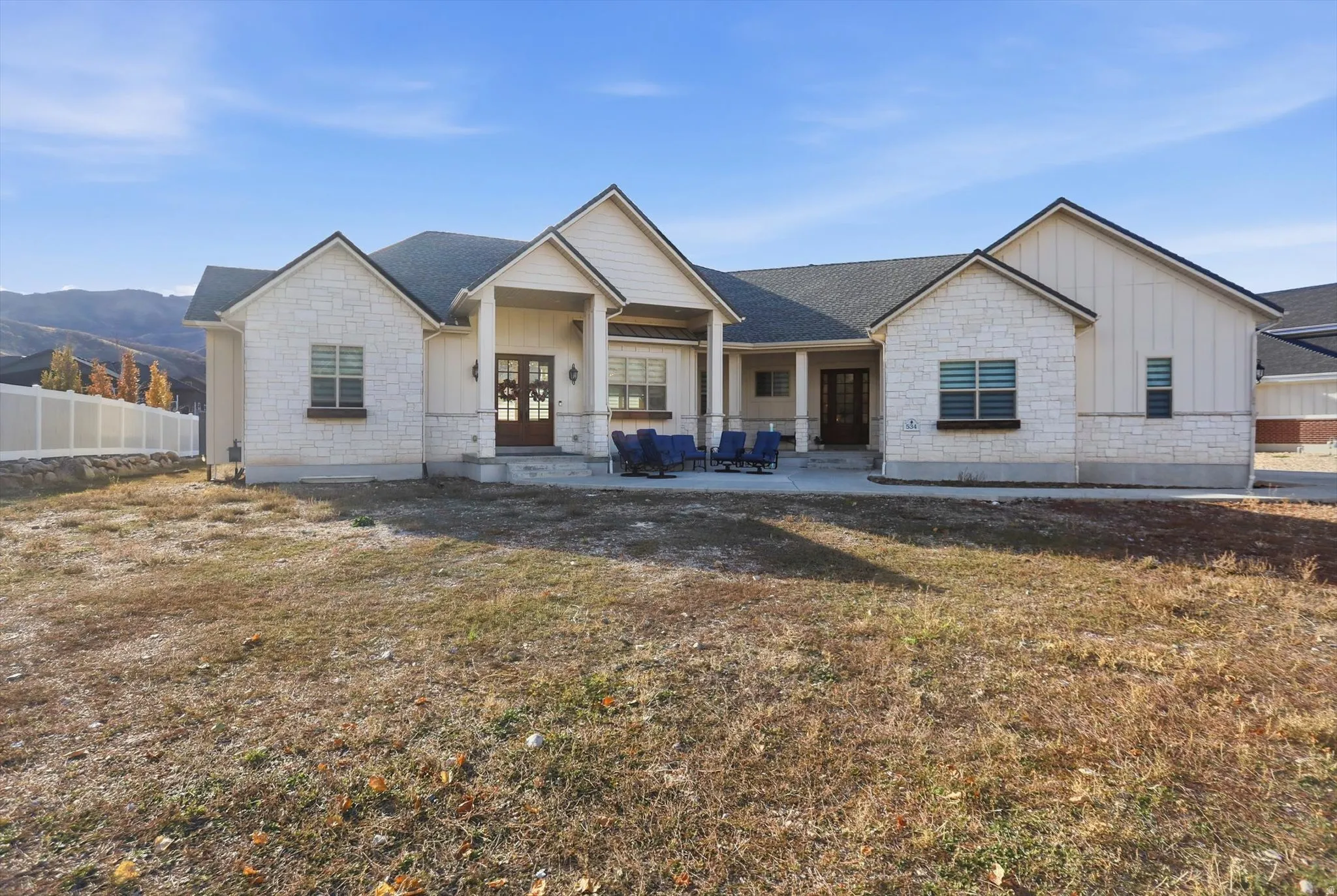 View of front of house with board and batten siding, stone siding, covered porch, french doors, and a mountain view