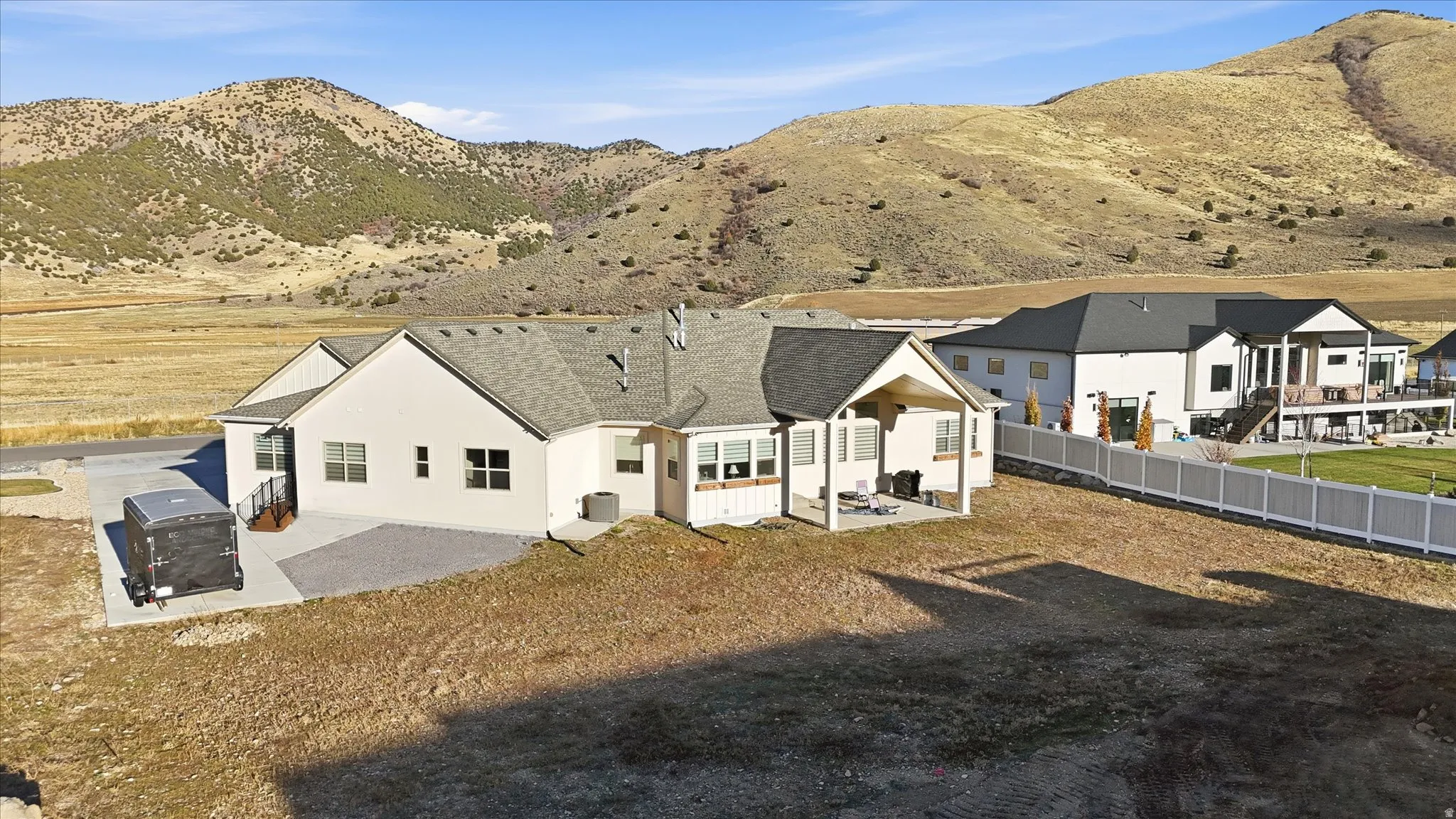 Rear view of house with a patio area, stucco siding, a shingled roof, and a mountain view