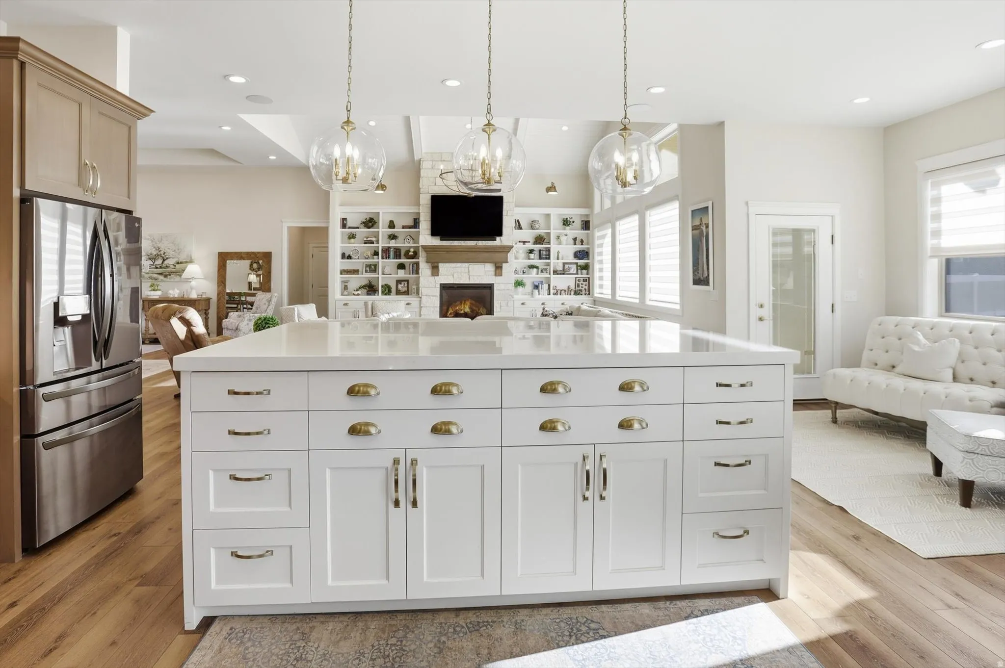 Kitchen featuring open floor plan, stainless steel fridge, a chandelier, and a lit fireplace