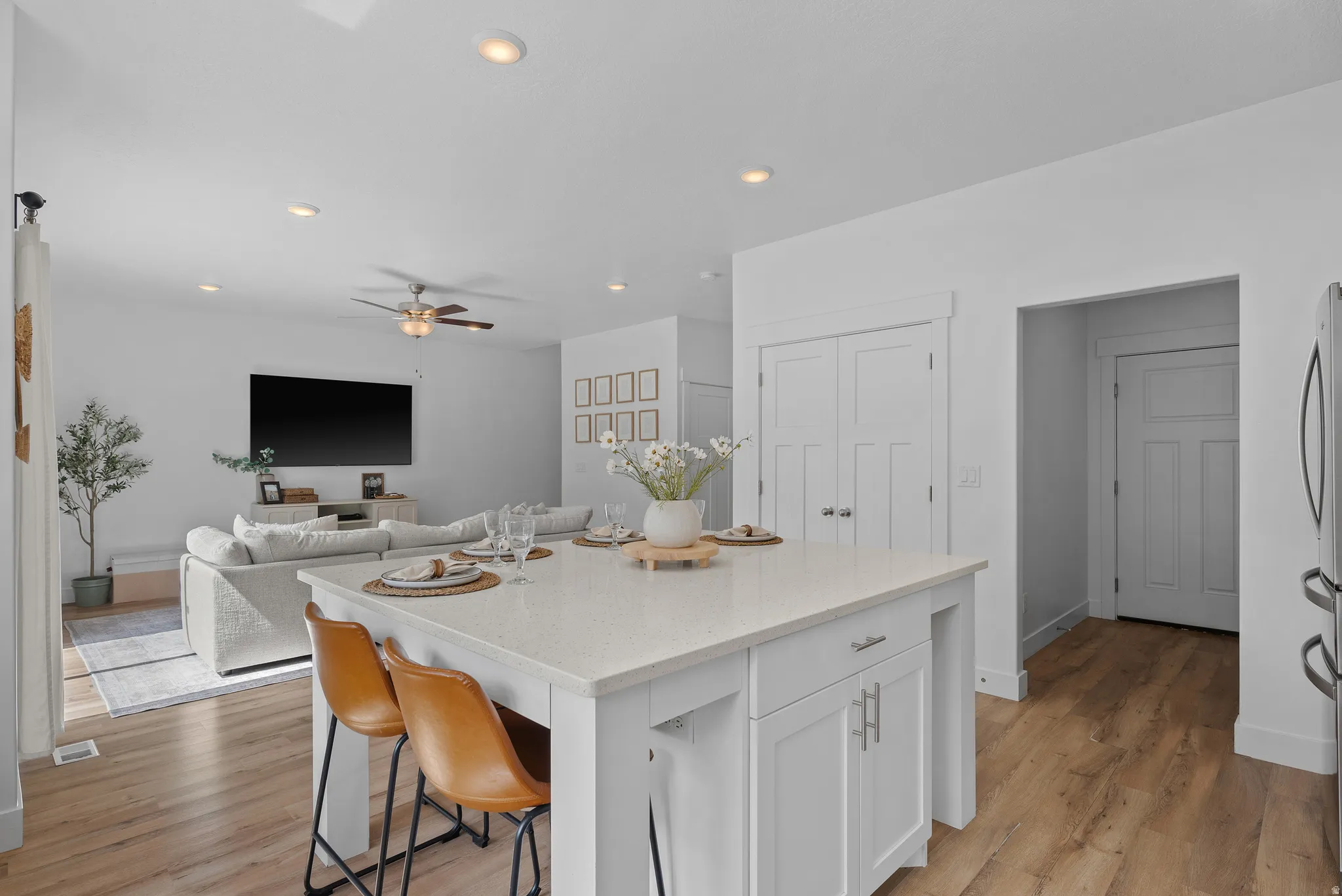 Kitchen with white cabinetry, a kitchen bar, a center island, open floor plan, and light stone counters