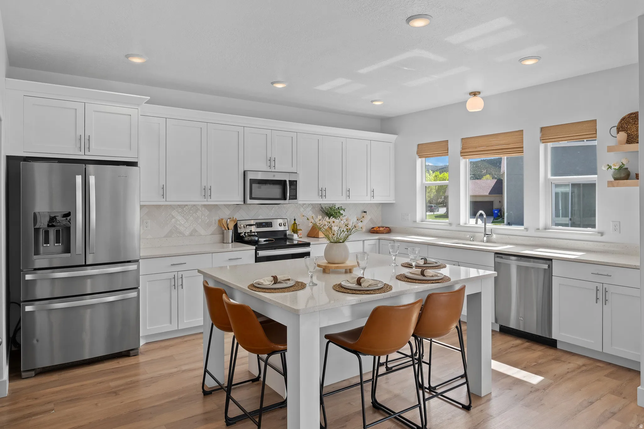 Kitchen with stainless steel appliances, white cabinetry, a kitchen bar, light stone counters, and recessed lighting