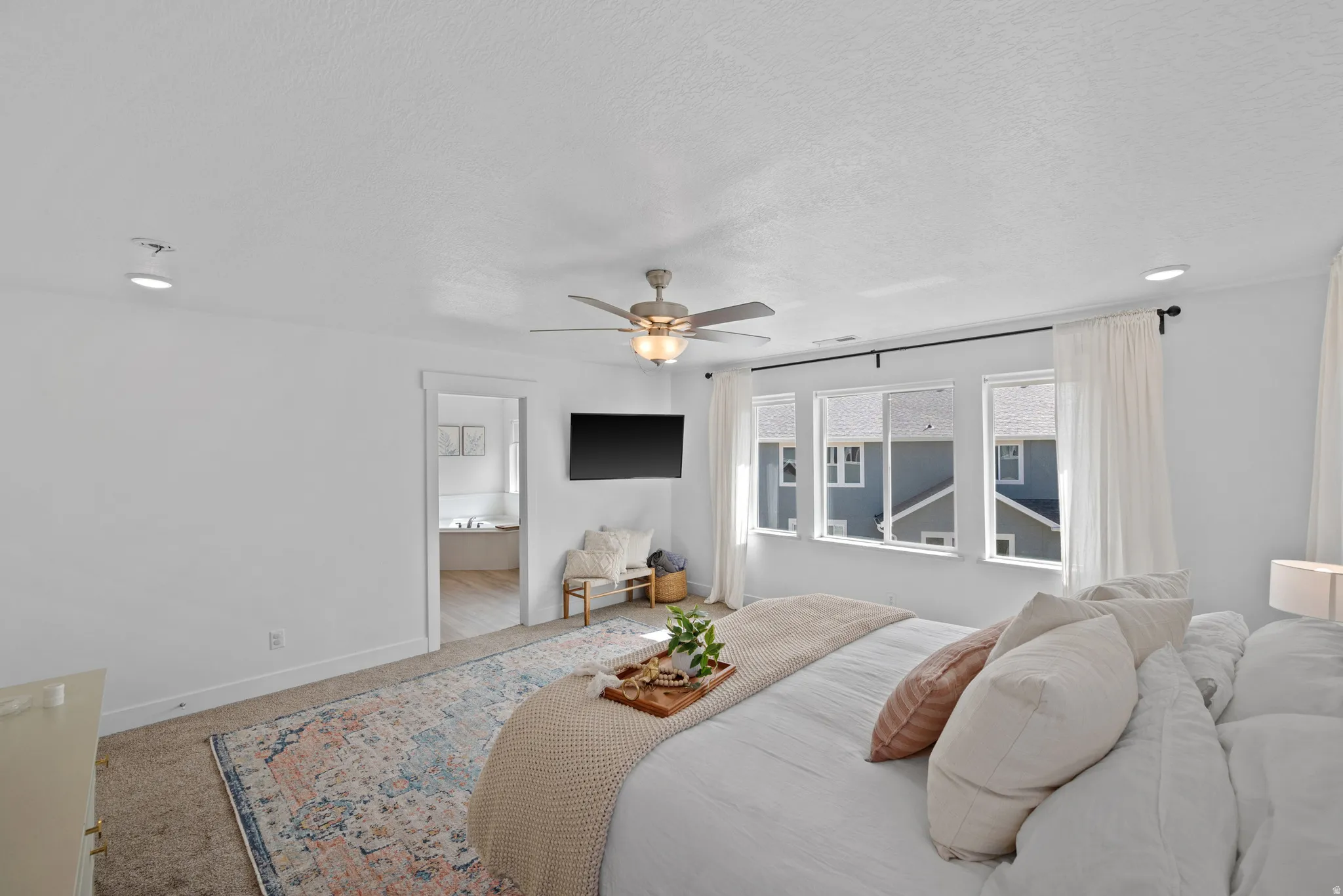 Bedroom featuring carpet floors, ceiling fan, ensuite bath, and a textured ceiling