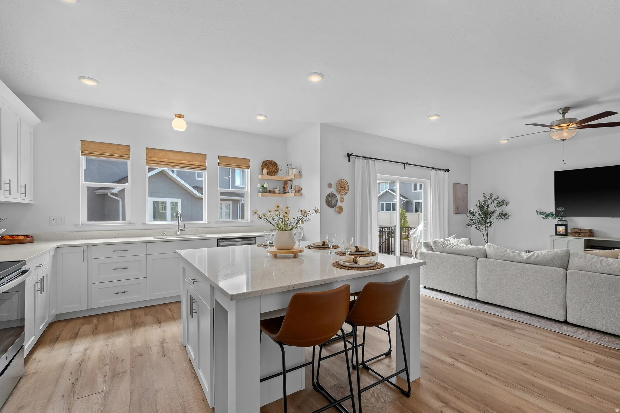 Kitchen with white cabinetry, light stone countertops, a center island, ceiling fan, and recessed lighting