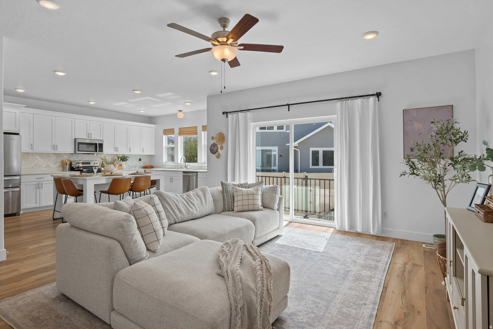 Living room with a ceiling fan, light wood finished floors, and recessed lighting