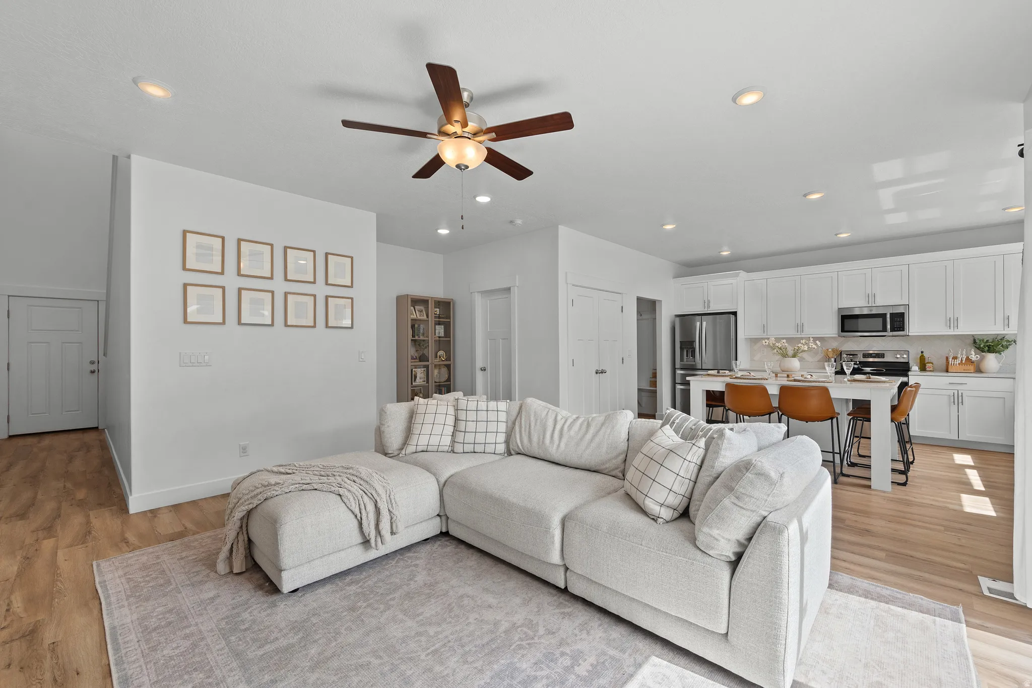 Living room featuring a ceiling fan, recessed lighting, and light wood-style flooring