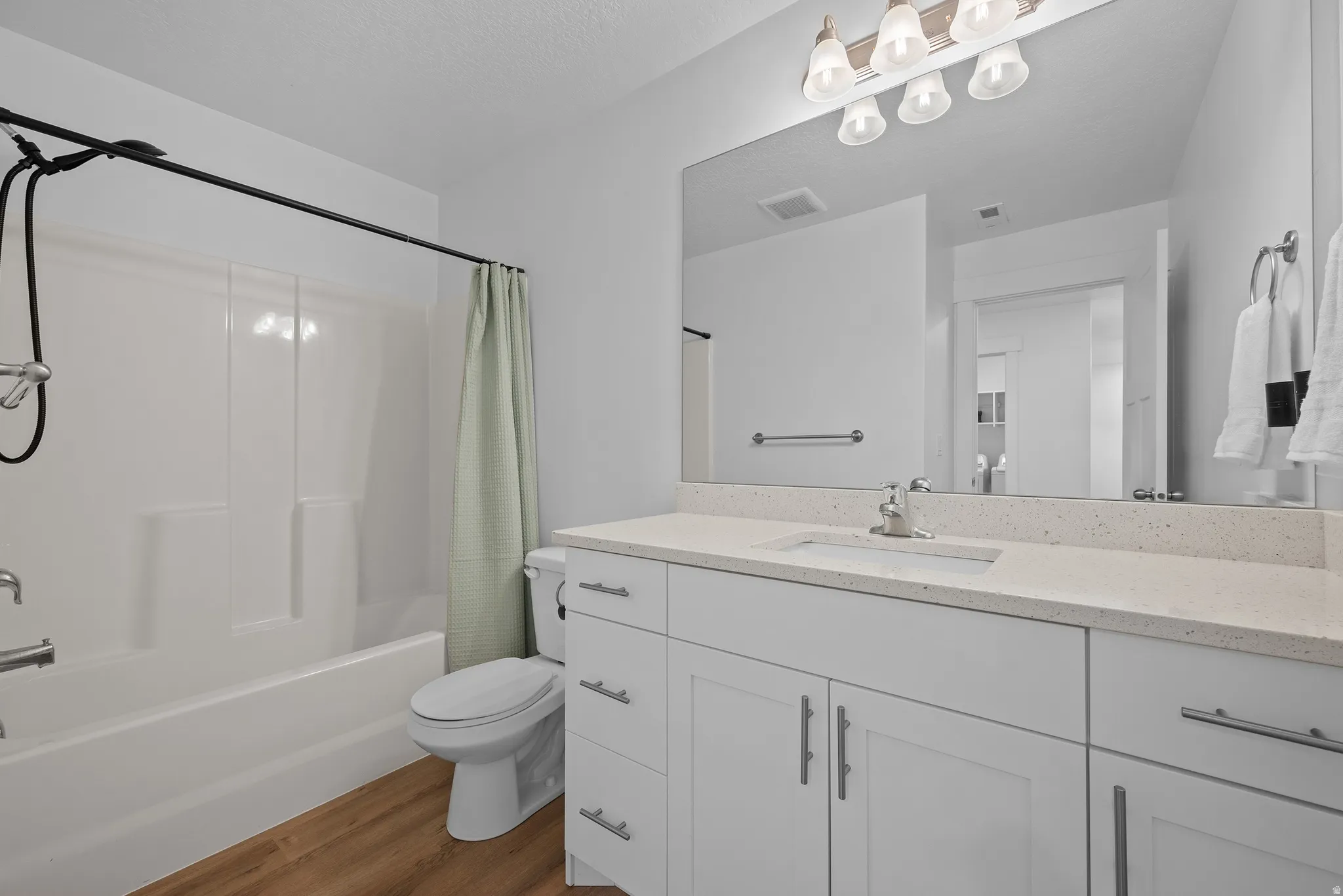 Full bathroom with vanity, dark wood finished floors, and shower / bathtub combination with curtain