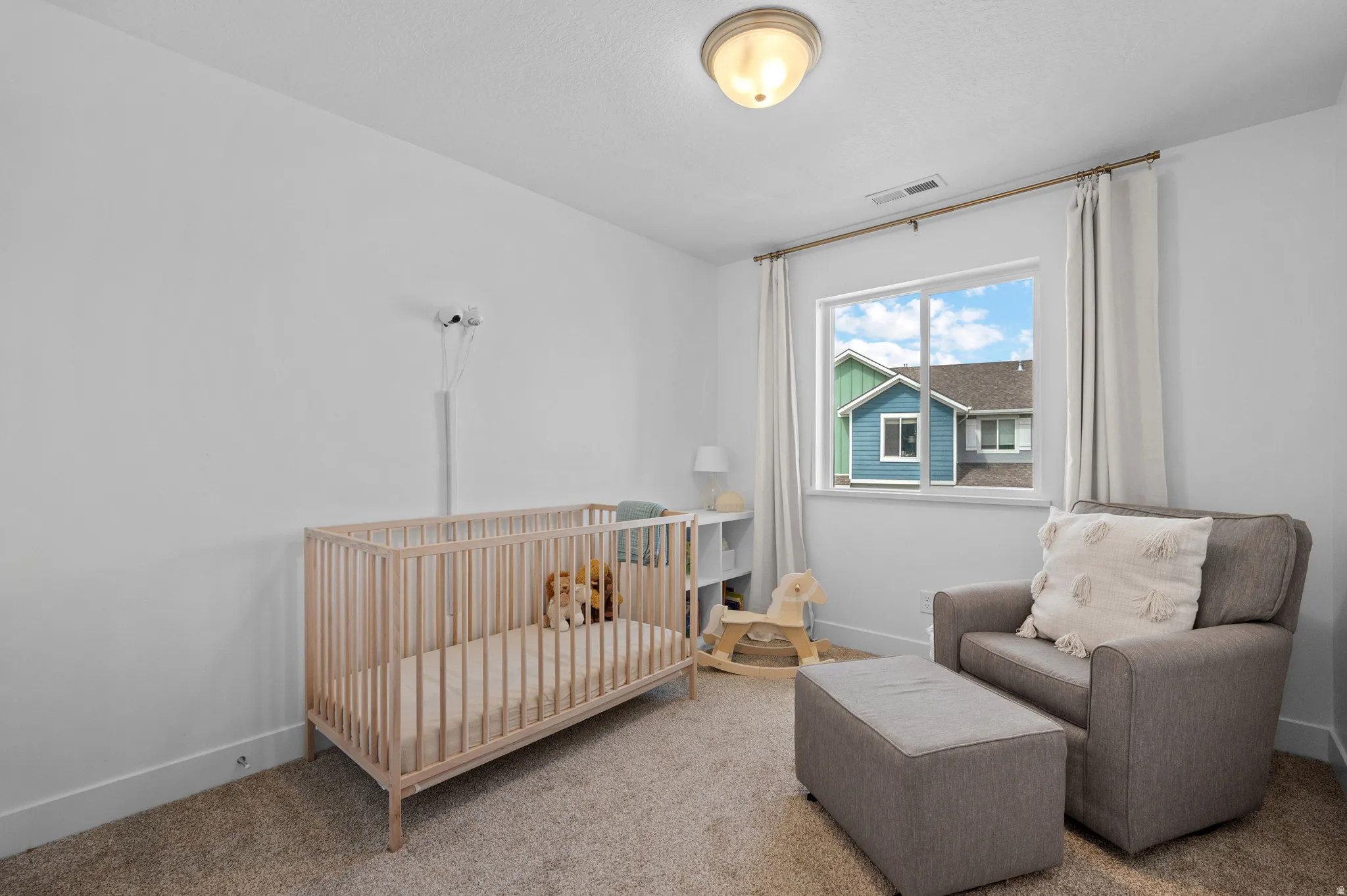 Carpeted bedroom featuring a nursery area and baseboards