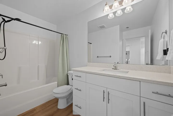 Full bathroom with vanity, dark wood finished floors, and shower / bathtub combination with curtain