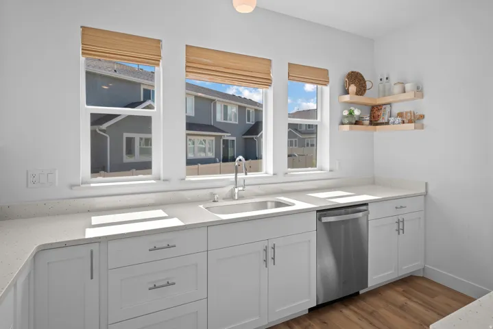 Kitchen featuring white cabinetry, dishwasher, light stone countertops, and dark wood finished floors