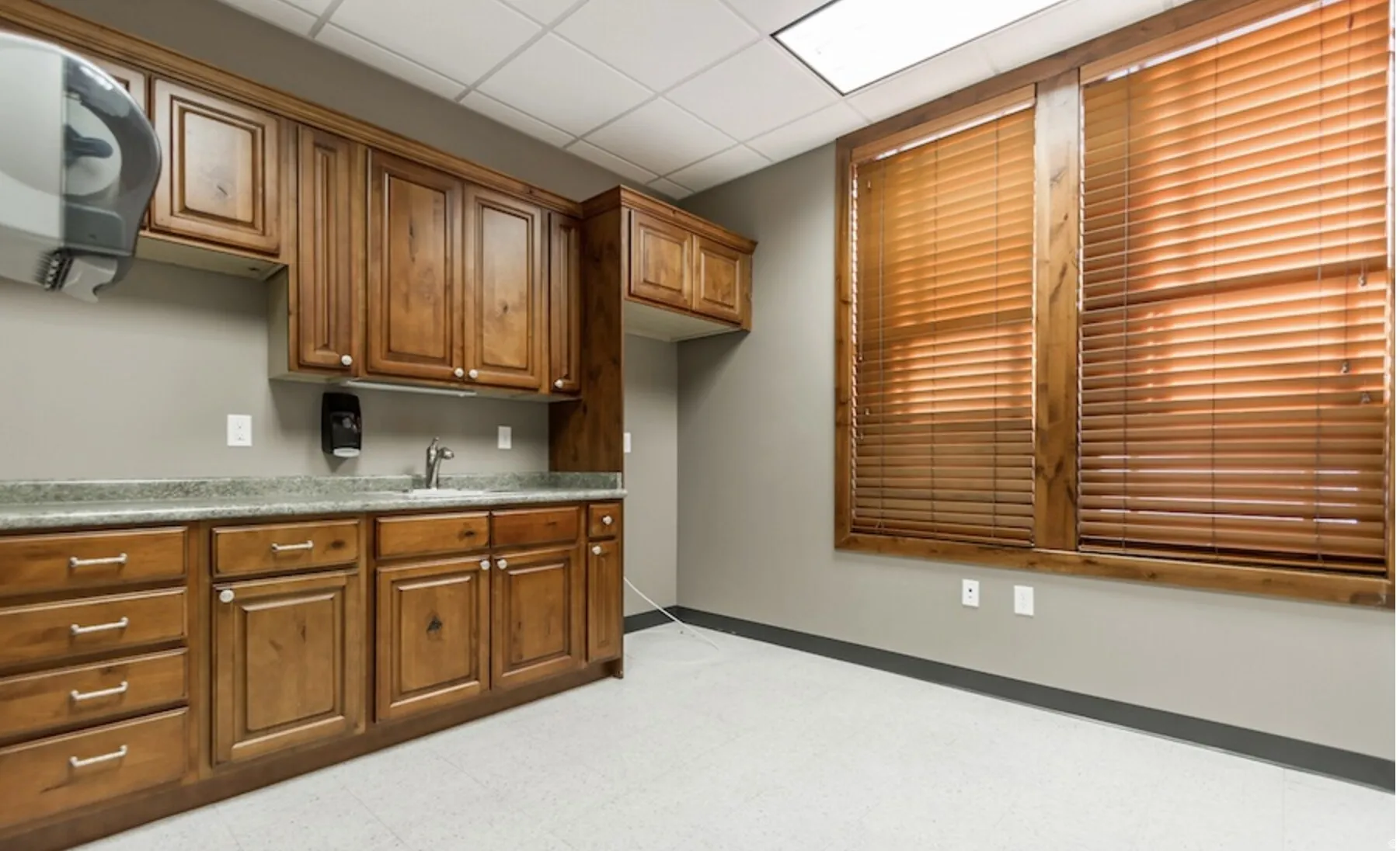 Kitchen featuring a paneled ceiling, wood finish cabinetry, light floors, and light countertops