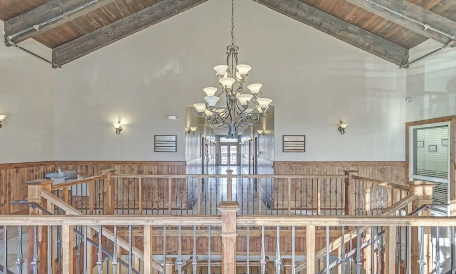 Detailed view of a wainscoted wall, a wooden ceiling with exposed beams, a chandelier, and wooden walls
