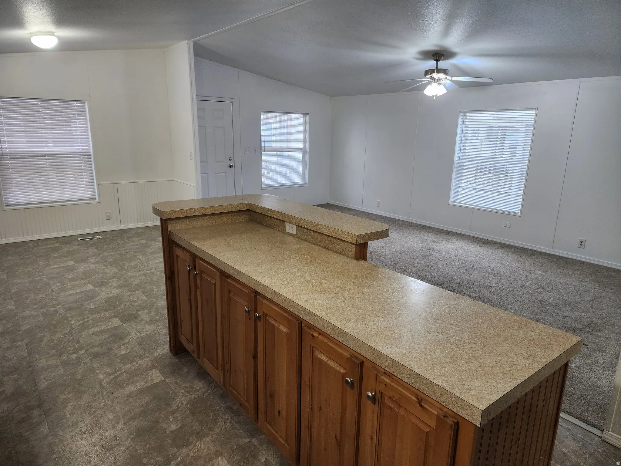 Kitchen with wood finish cabinets, open floor plan, light countertops, a center island, and a decorative wall