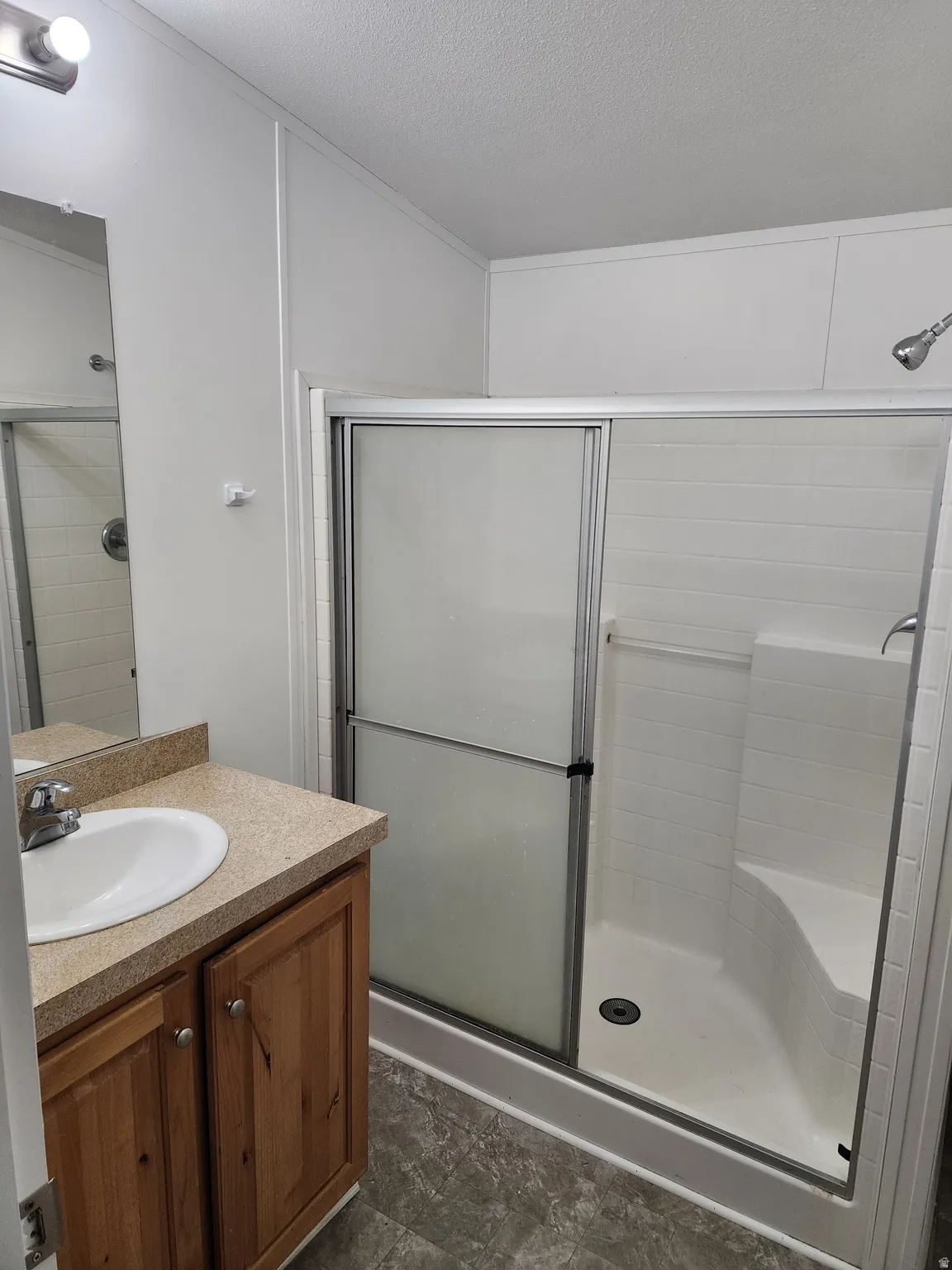 Bathroom with vanity, a stall shower, and a textured ceiling