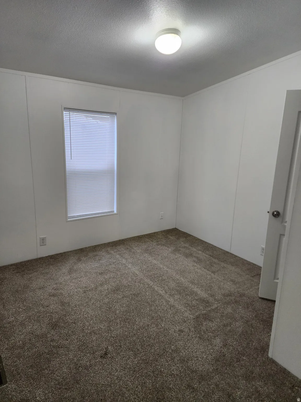 Spare room featuring a decorative wall, dark carpet, and a textured ceiling