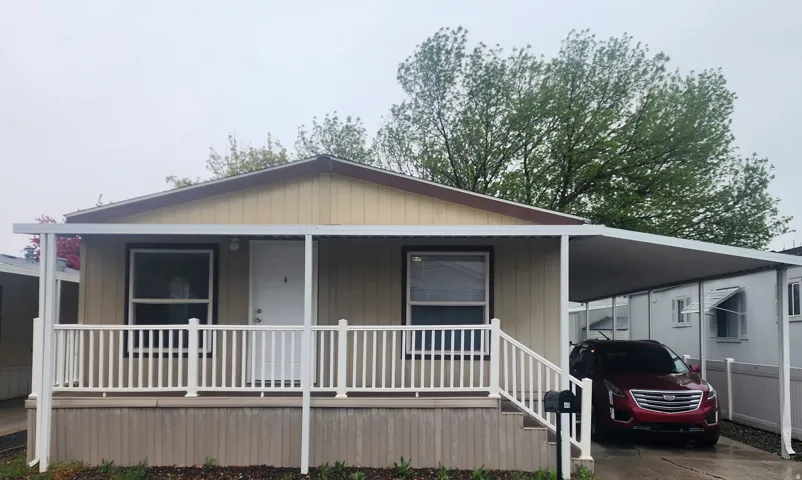 Manufactured / mobile home featuring an attached carport, a porch, and driveway