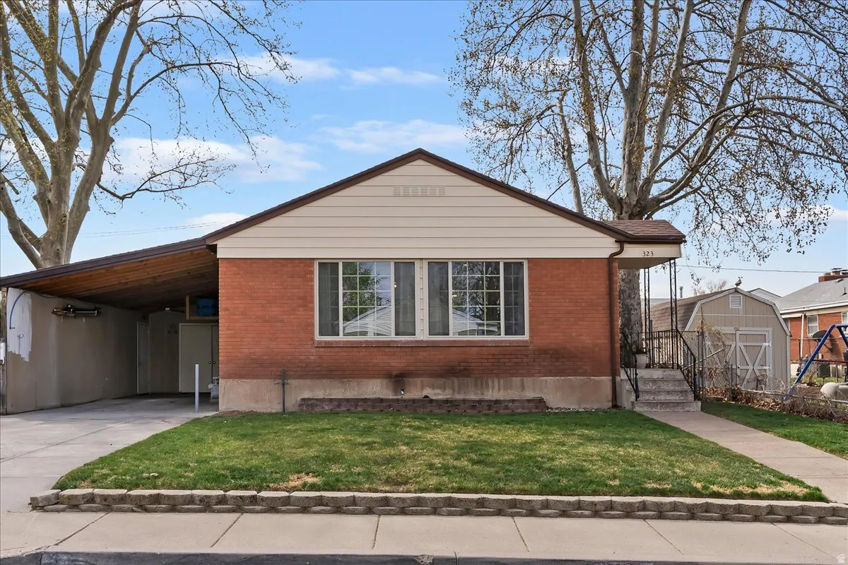 Bungalow with concrete driveway, a front lawn, an attached carport, and brick siding
