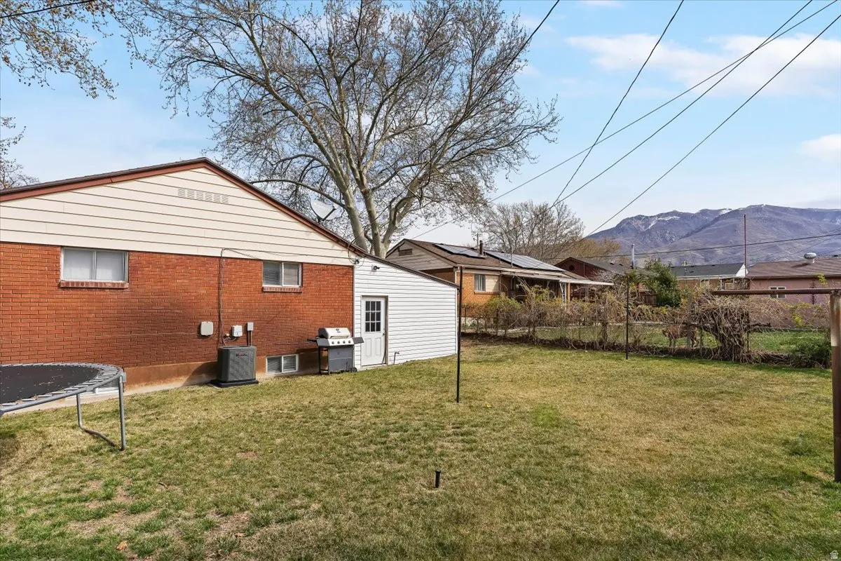 Back of property featuring brick siding, a trampoline, and a mountain view