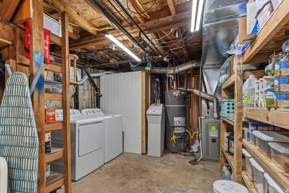 Unfinished basement featuring secured water heater, a water softener, washer and clothes dryer, and heating unit