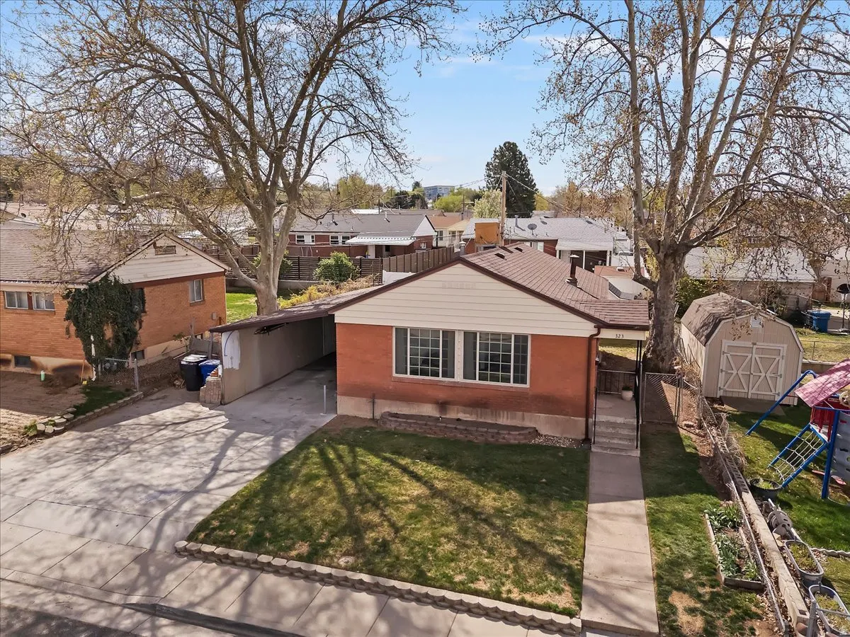 View of front facade with a residential view, an attached carport, driveway, a playground, and a shed