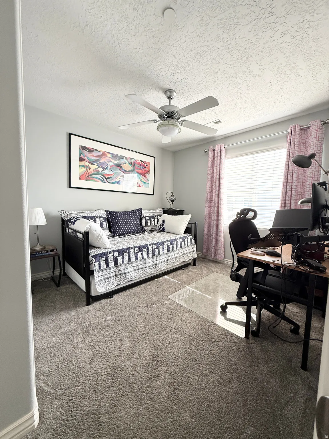 Carpeted bedroom with a desk, a textured ceiling, and a ceiling fan