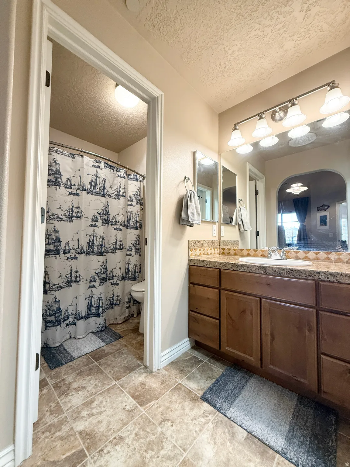 Full bathroom featuring vanity, a textured ceiling, and a shower with shower curtain