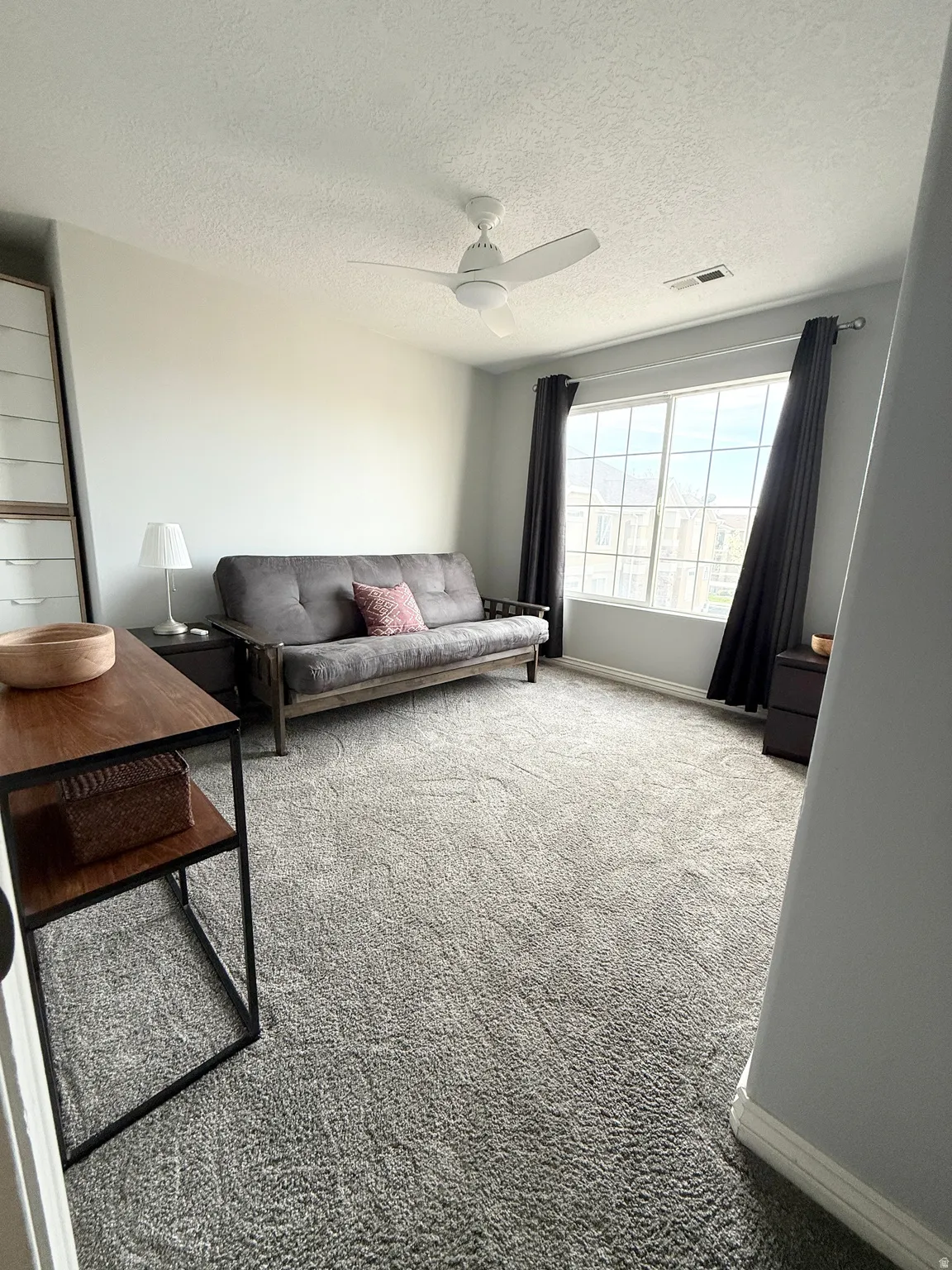 Carpeted living area with a textured ceiling and ceiling fan