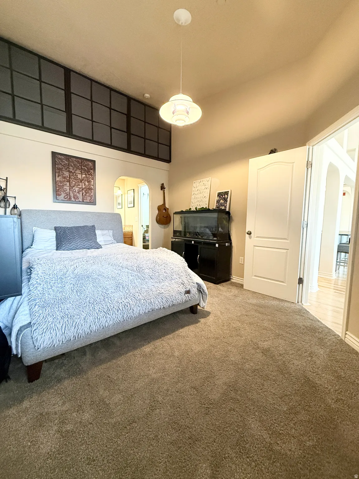 Bedroom featuring arched walkways, carpet floors, and a high ceiling