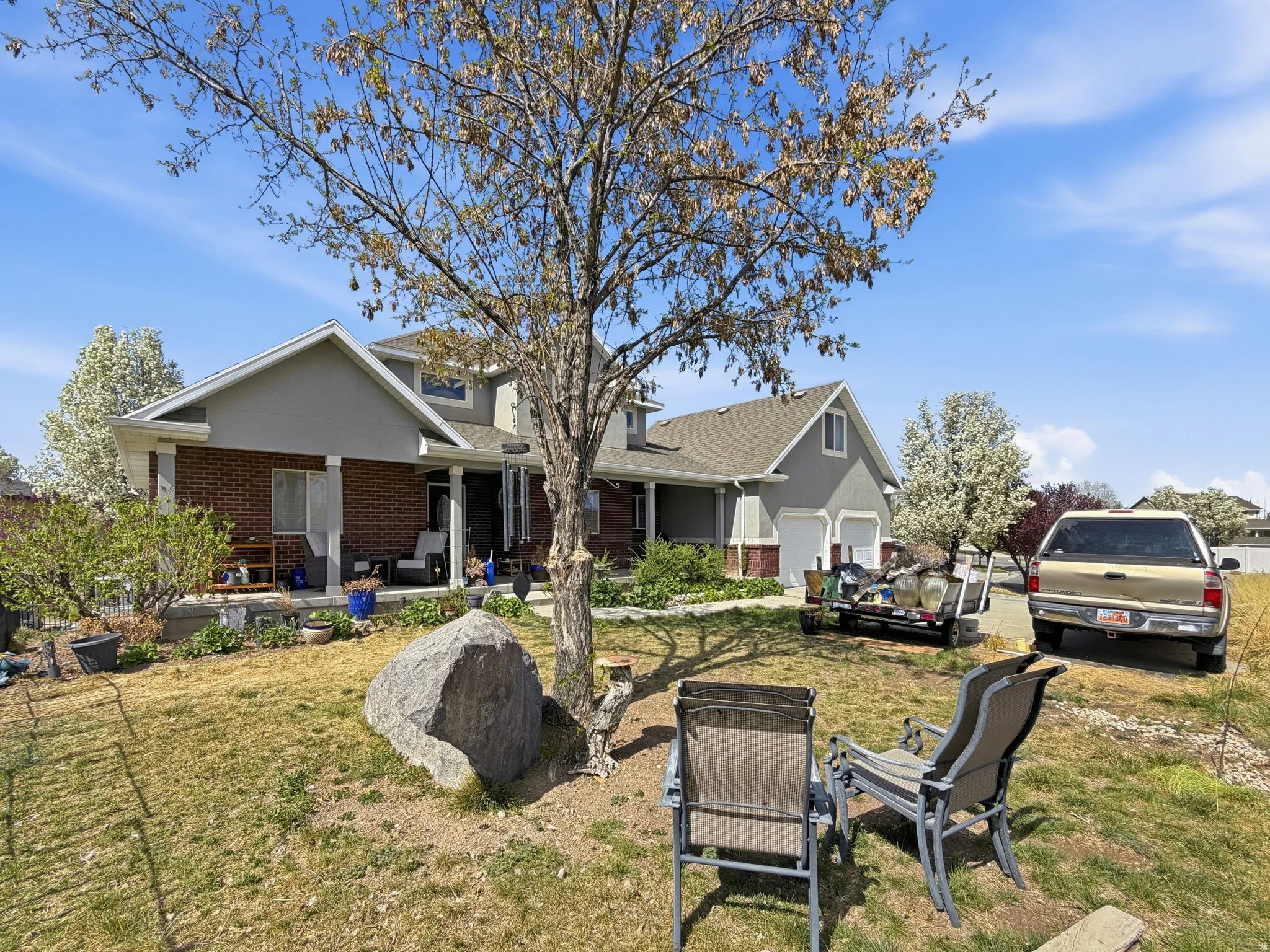 View of front of home featuring brick siding, a patio area, a front lawn, and a garage