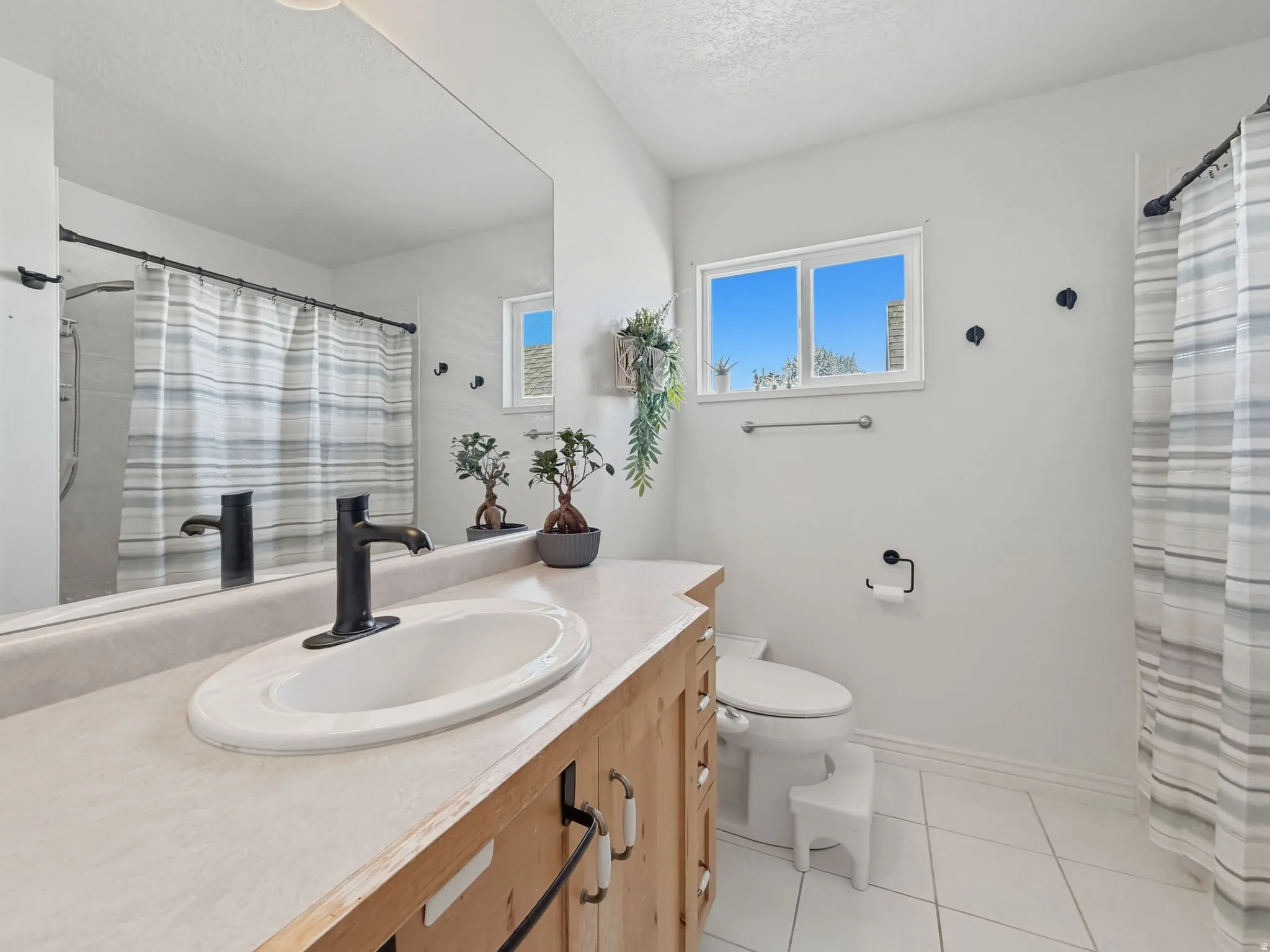 Bathroom with vanity, a shower with curtain, light tile patterned flooring, and a textured ceiling