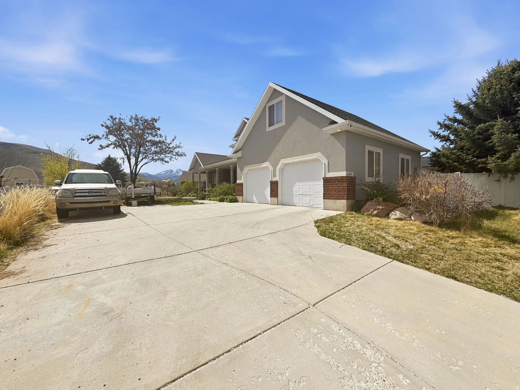 View of side of home with stucco siding, concrete driveway, and brick siding
