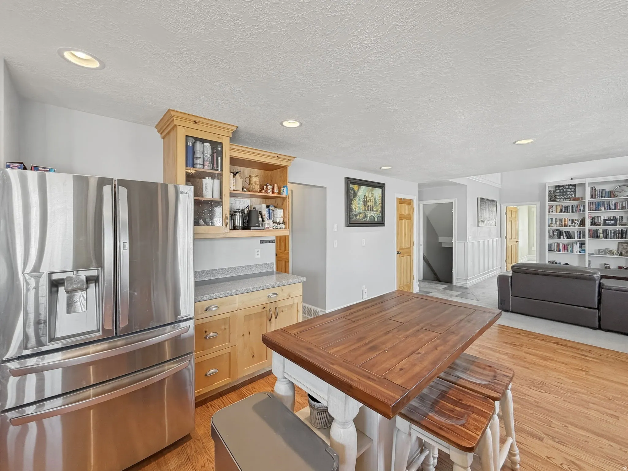Kitchen featuring stainless steel fridge, light wood-style flooring, a textured ceiling, recessed lighting, and light countertops