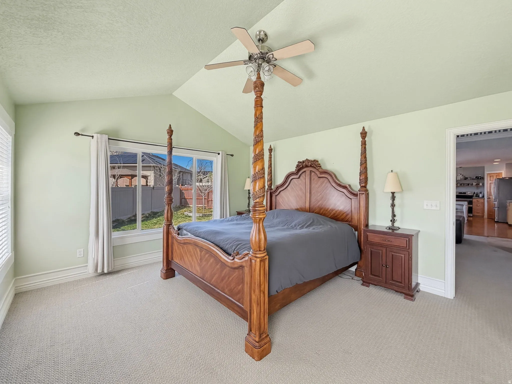 Bedroom featuring light colored carpet, ceiling fan, freestanding refrigerator, and a textured ceiling