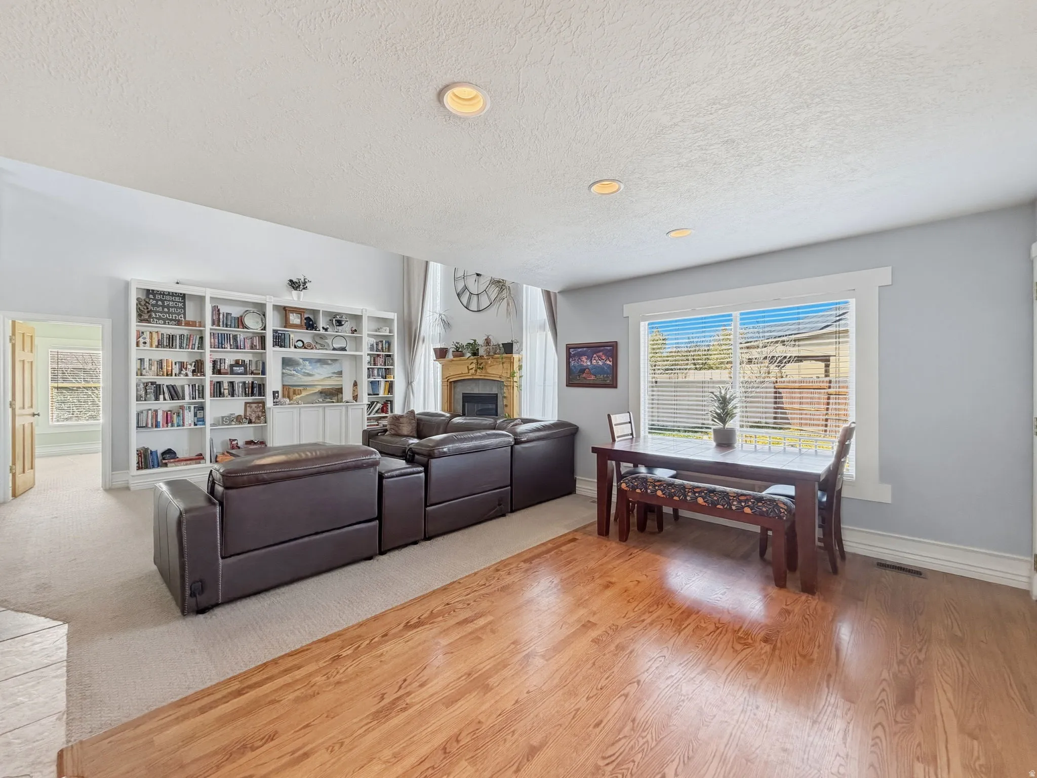 Living room with a fireplace, light wood-style flooring, a textured ceiling, and recessed lighting